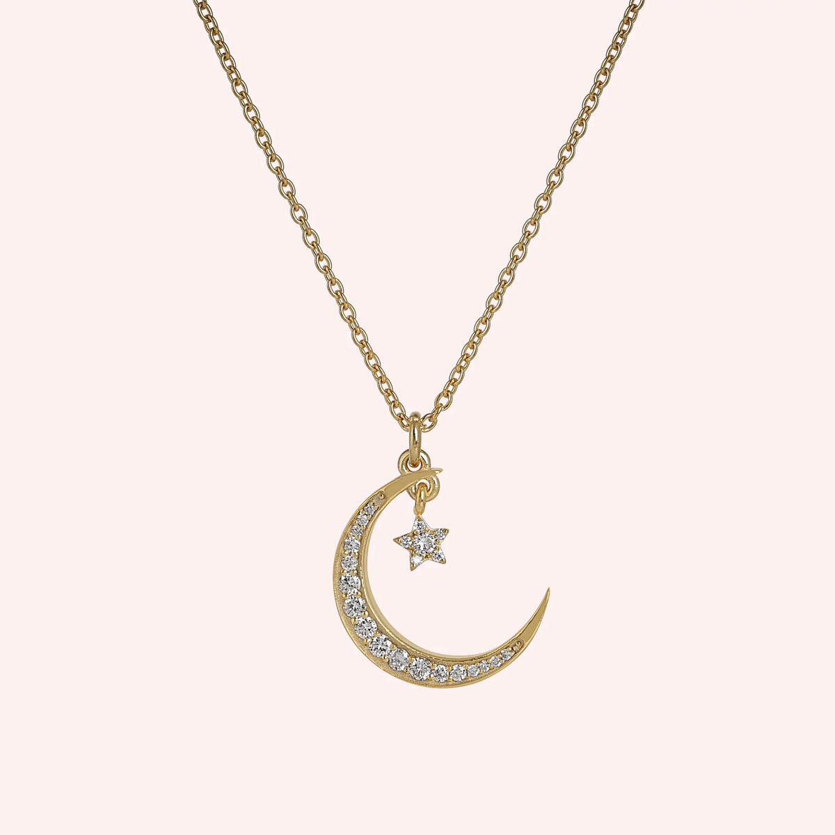 Moon_necklace_in_gold_plated_silver_with_a_small_star_charm_at_front_angle_view_on_solid_pink_background