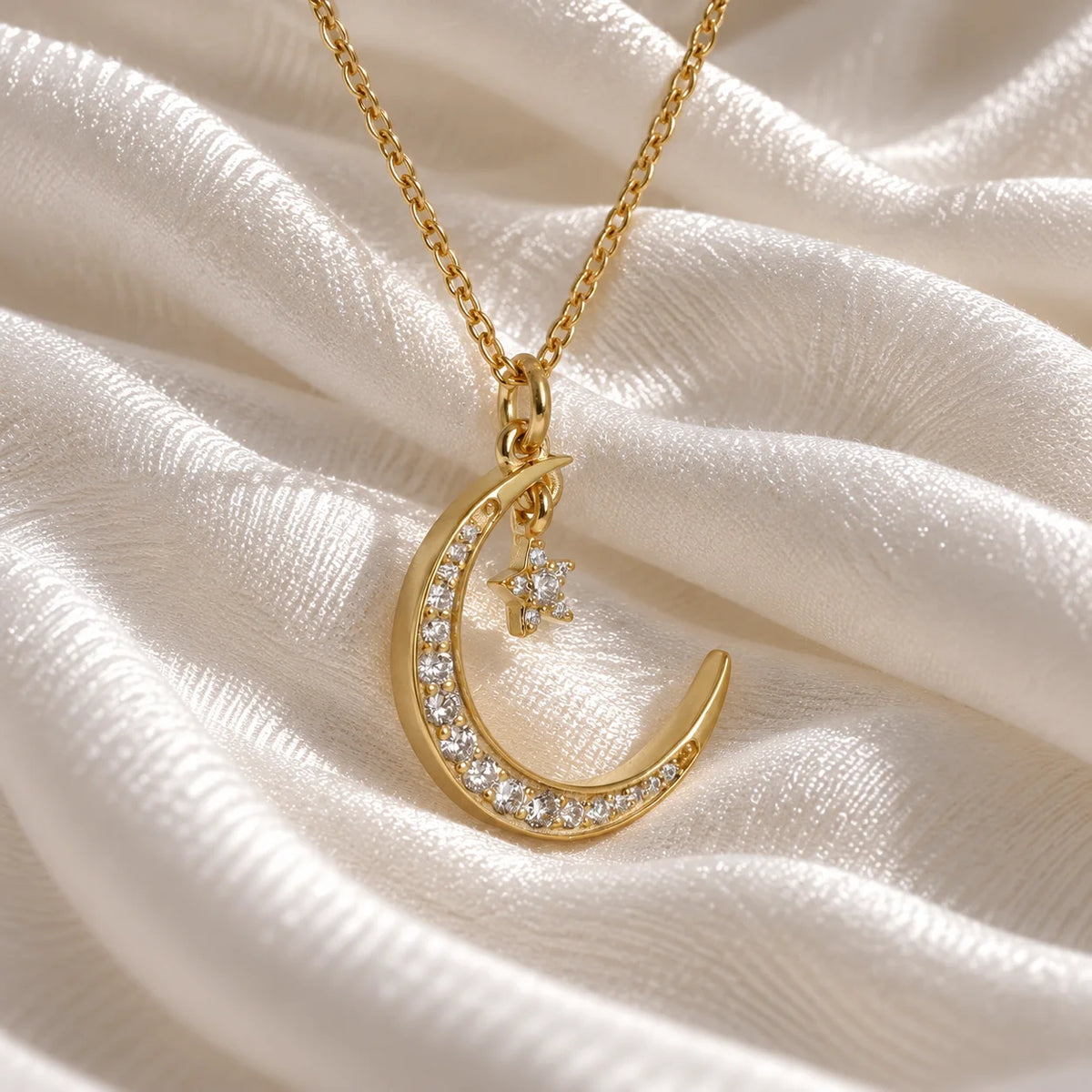 Moon_necklace_in_gold_plated_silver_with_a_small_star_charm_at_slight_angle_view_on_soft_fabric_background