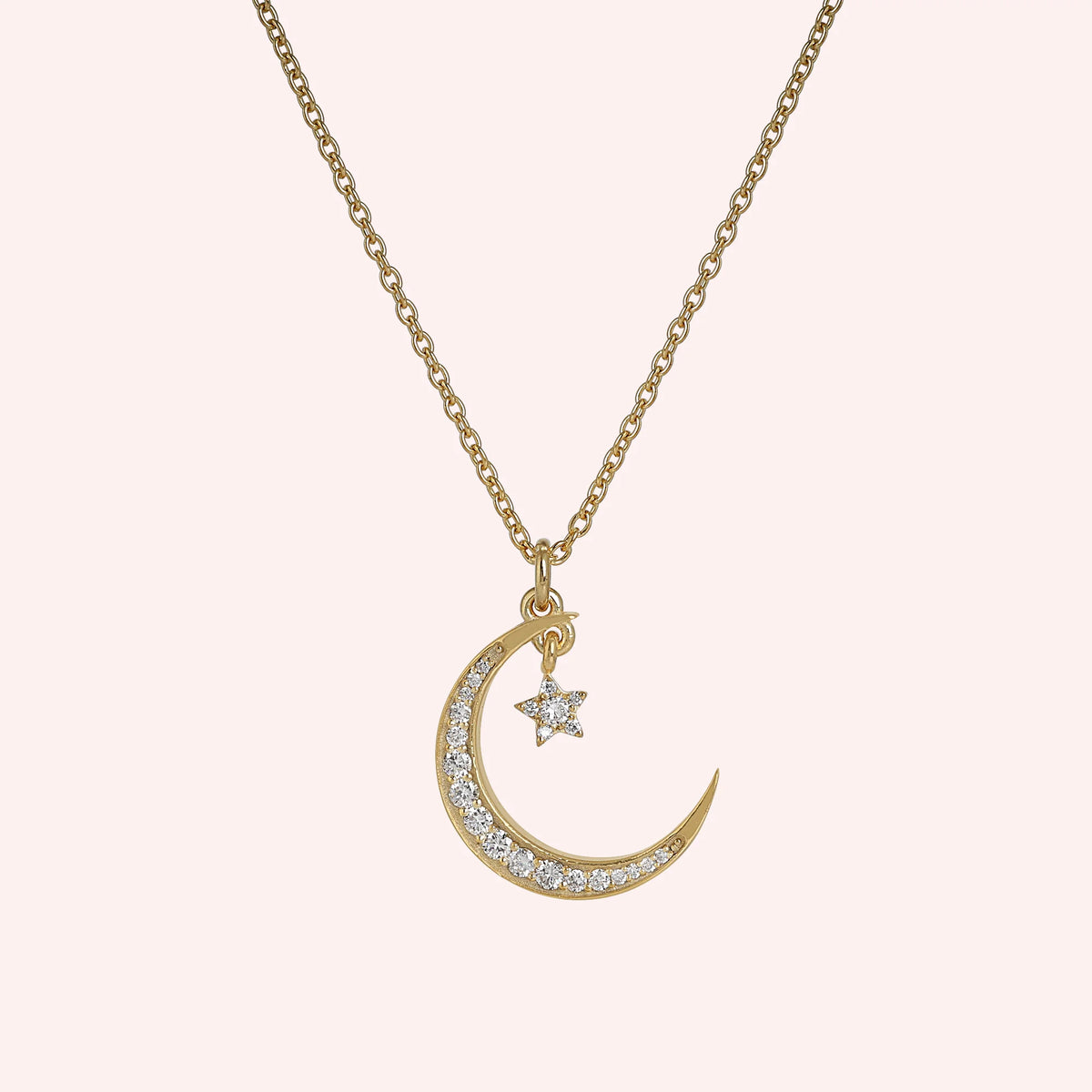 Moon_necklace_in_gold_plated_silver_with_a_small_star_charm_at_front_angle_view_on_solid_pink_background