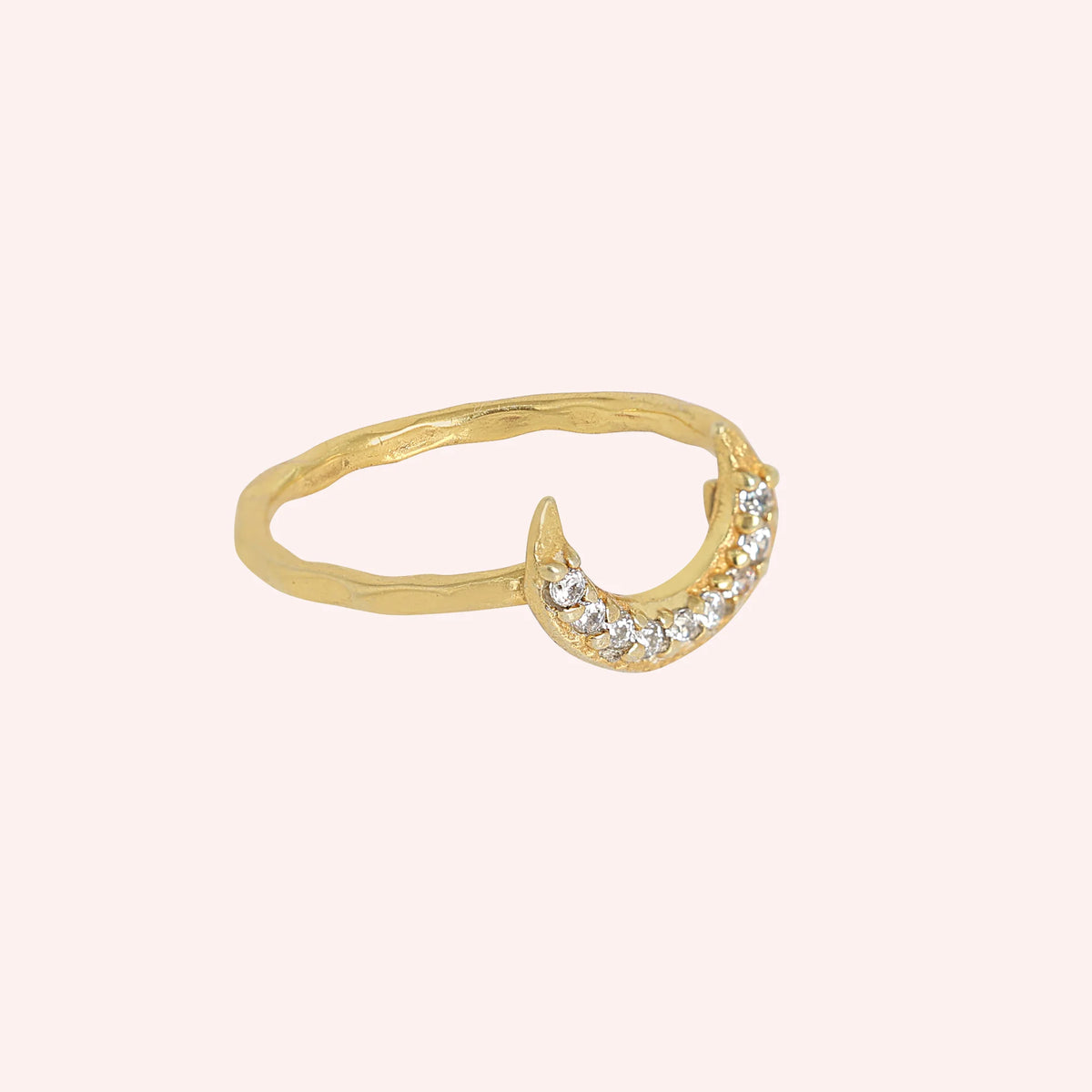 Moon_ring_in_gold_plated_silver_in_a_crescent_moon_design_with_CZ_stones_at_side_angle_view_on_solid_pink_background