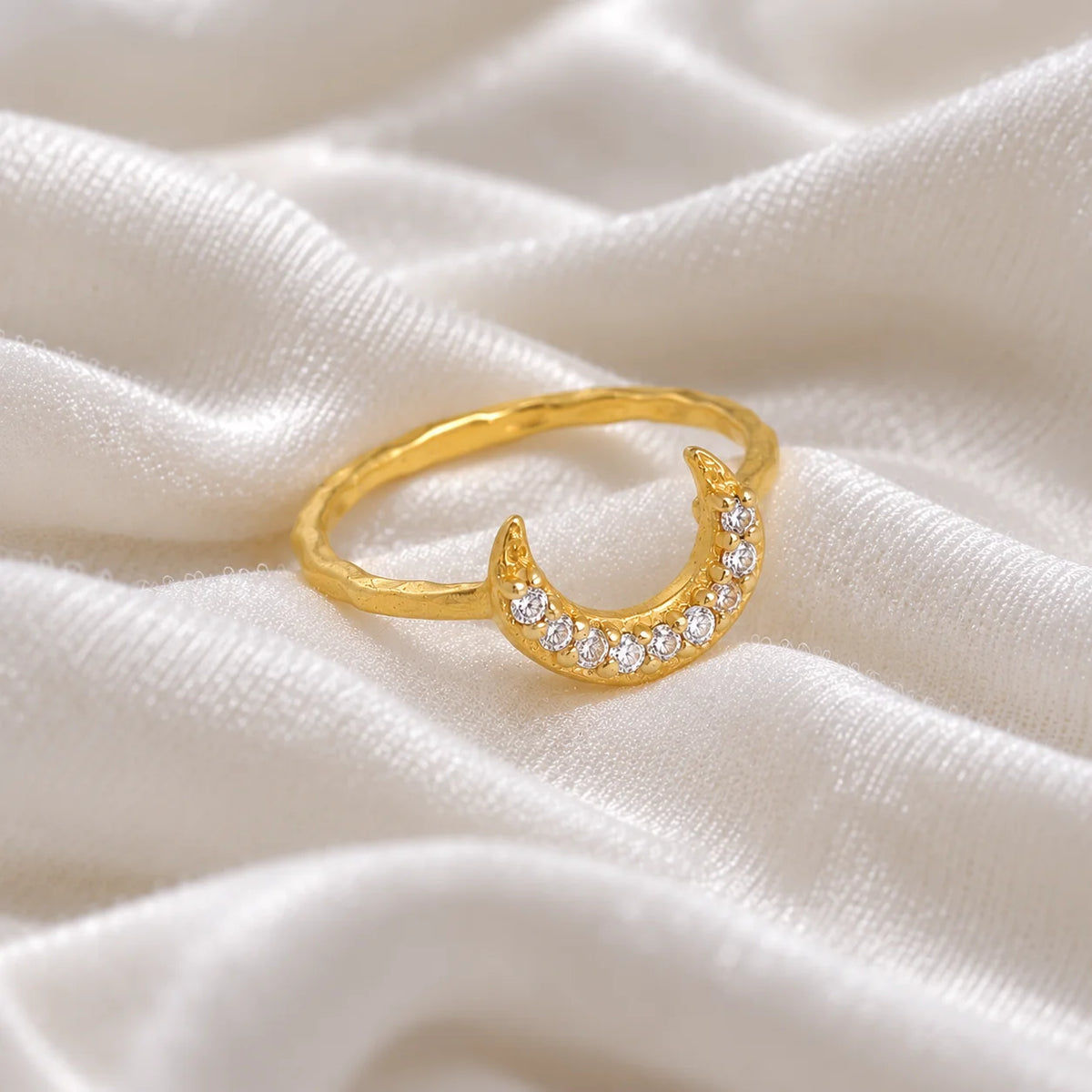Moon_ring_in_gold_plated_silver_in_a_crescent_moon_design_with_CZ_stones_at_side_angle_view_on_soft_fabric_background