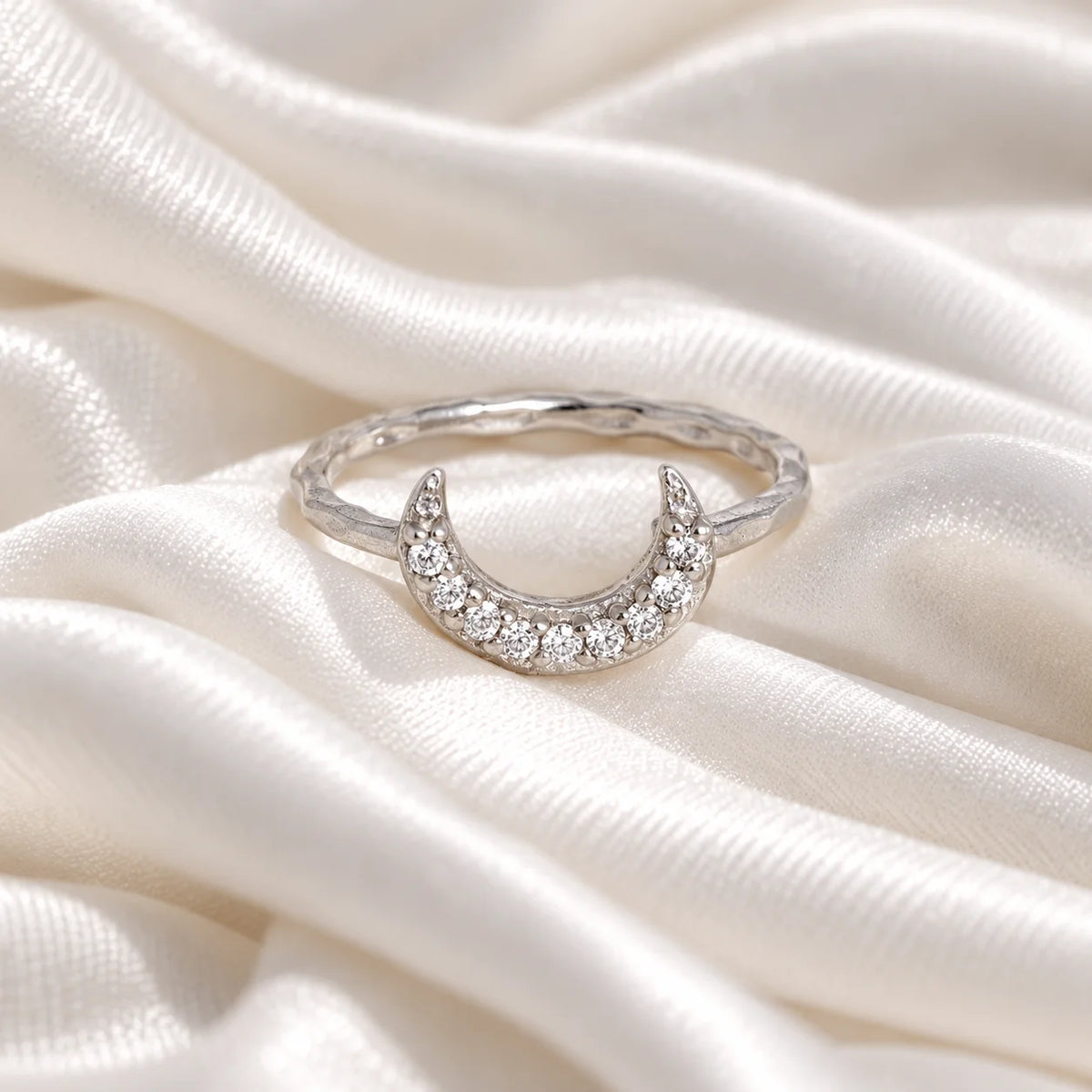 Moon_ring_in_sterling_silver_with_a_crescent_moon_design_at_front_angle_view_on_soft_fabric_background