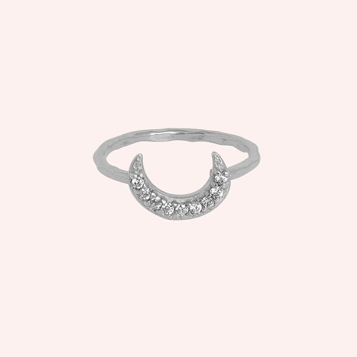 Moon_ring_in_sterling_silver_in_a_crescent_moon_design_with_CZ_stones_at_front_angle_view_on_solid_pink_background