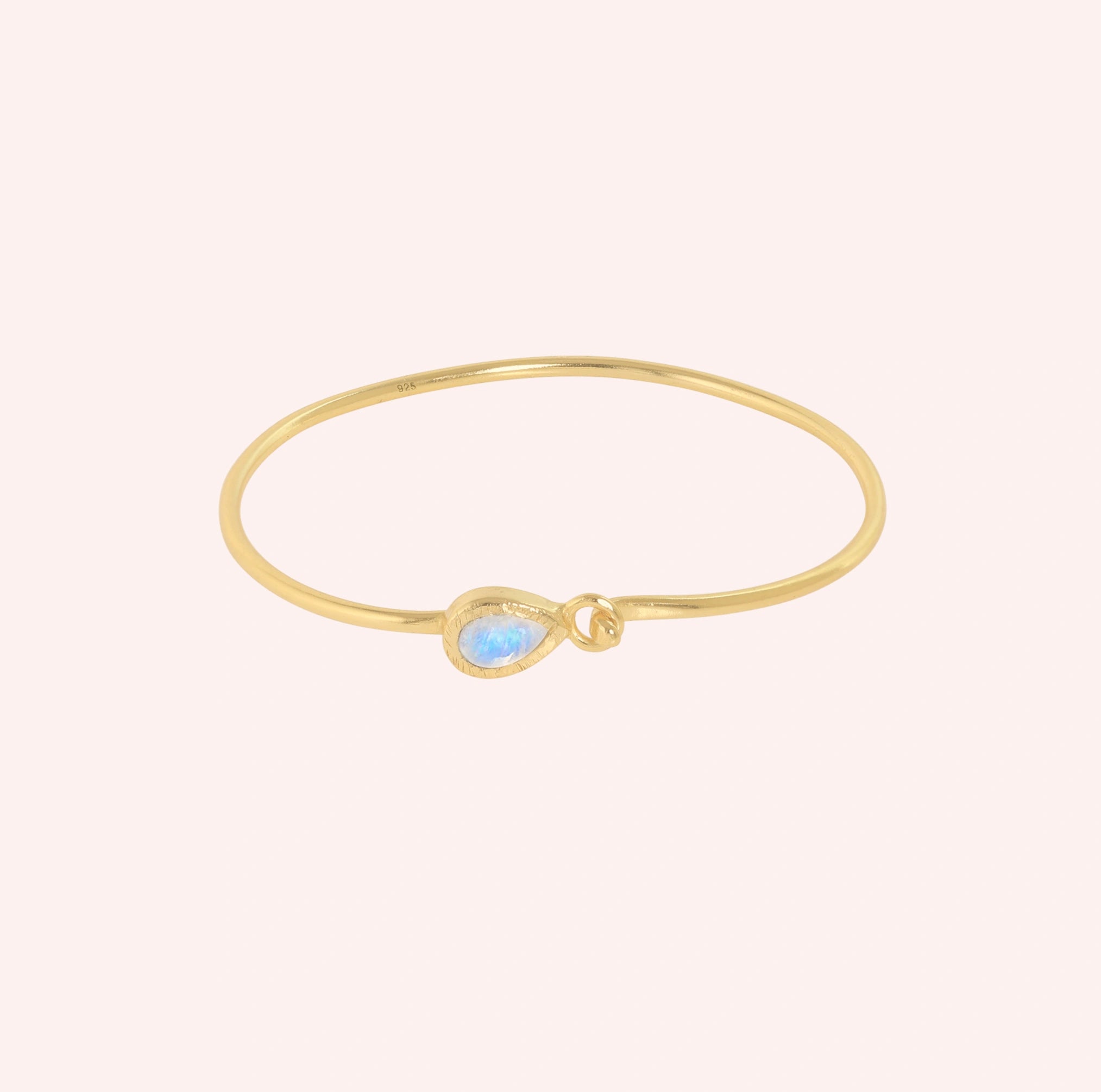 Moonstone_bracelet_in_gold_plated_silver_with_teardrop_moonstone_at_front_angle_view_on_solid_pink_background