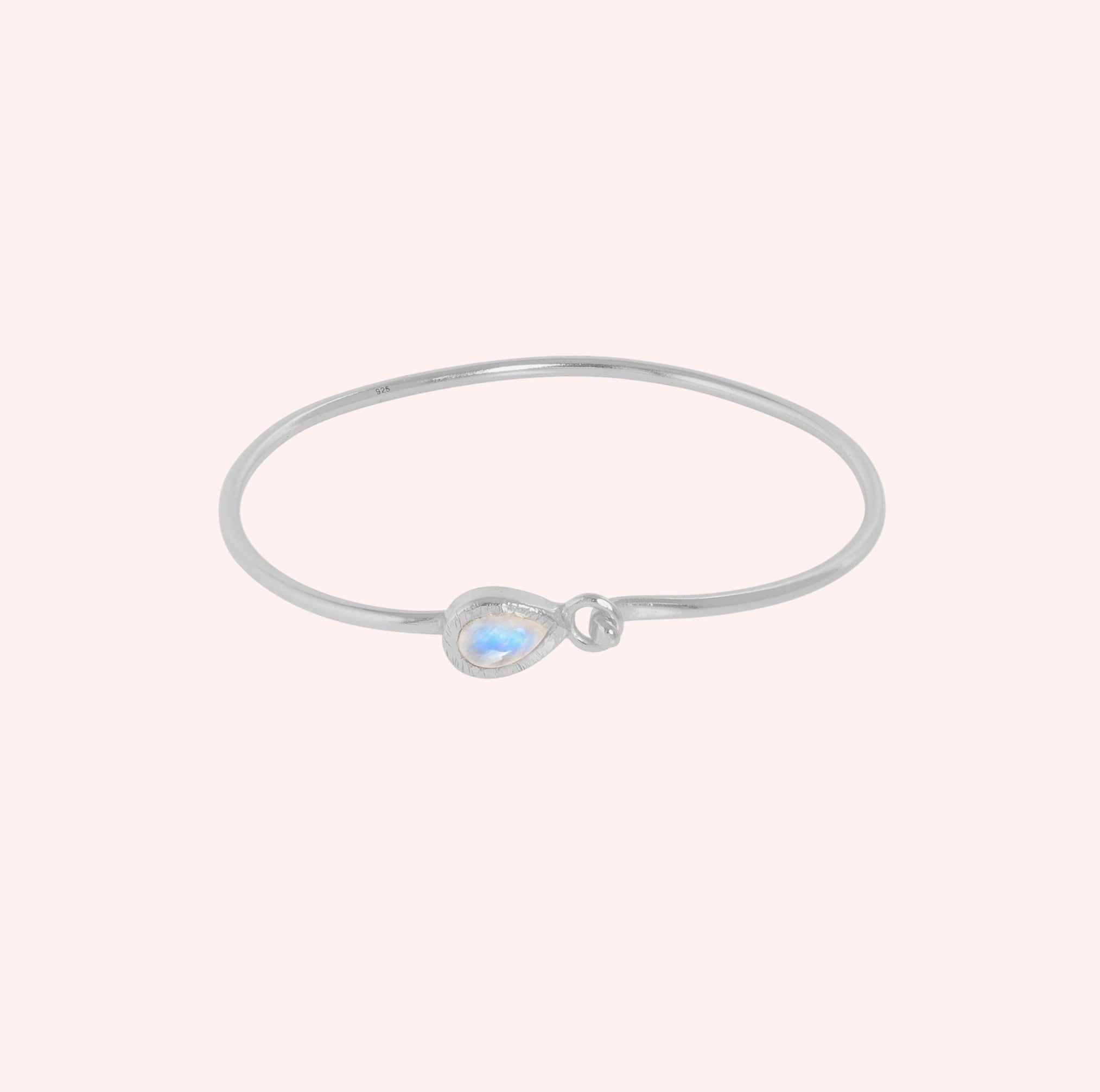 Moonstone_bracelet_in_sterling_silver_with_teardrop_moonstone_at_front_angle_view_on_solid_pink_background