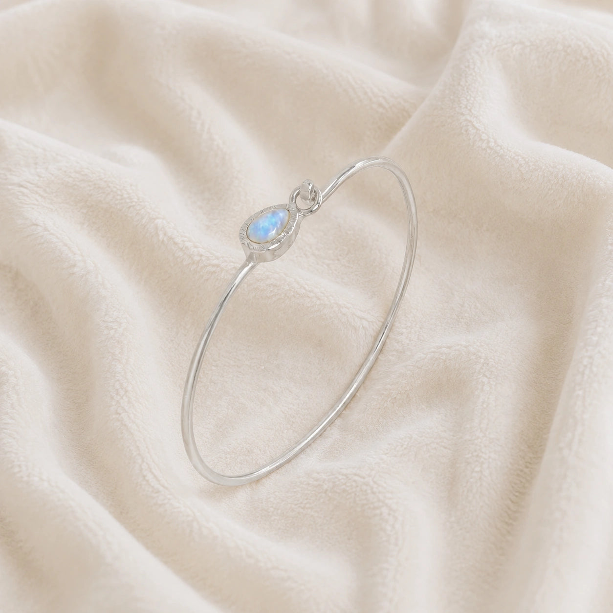 Moonstone_bracelet_in_sterling_silver_with_teardrop_moonstone_at_slight_angle_view_on_soft_fabric_background