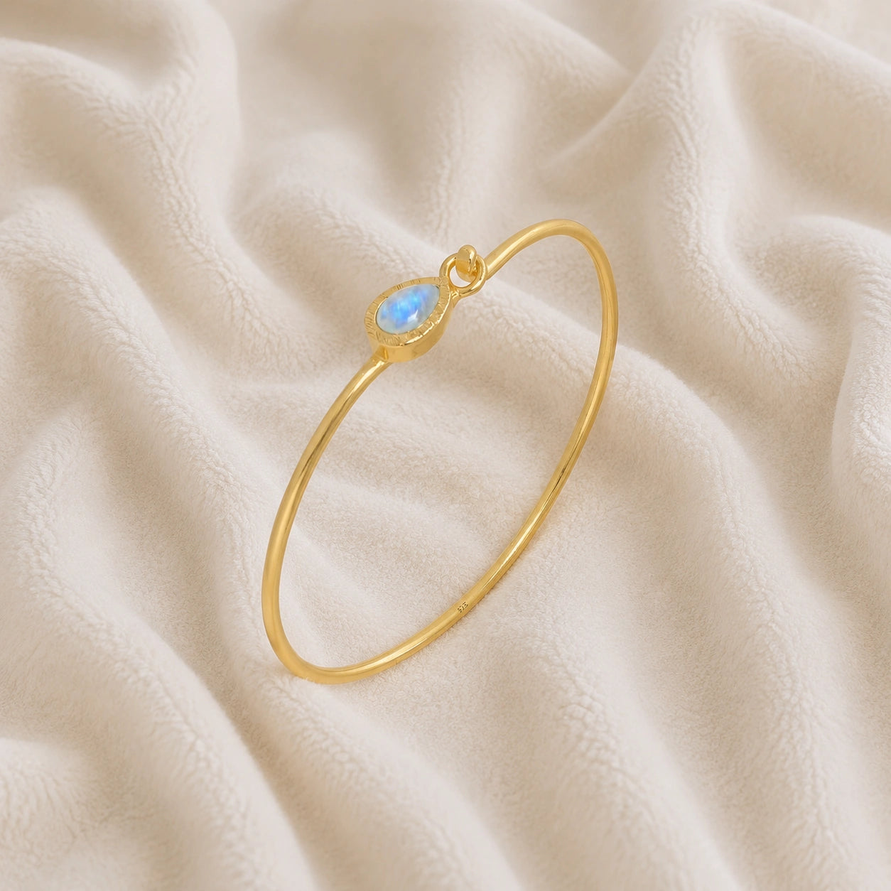 Moonstone_bracelet_in_gold_plated_silver_with_teardrop_moonstone_at_slight_angle_view_on_soft_fabric_background