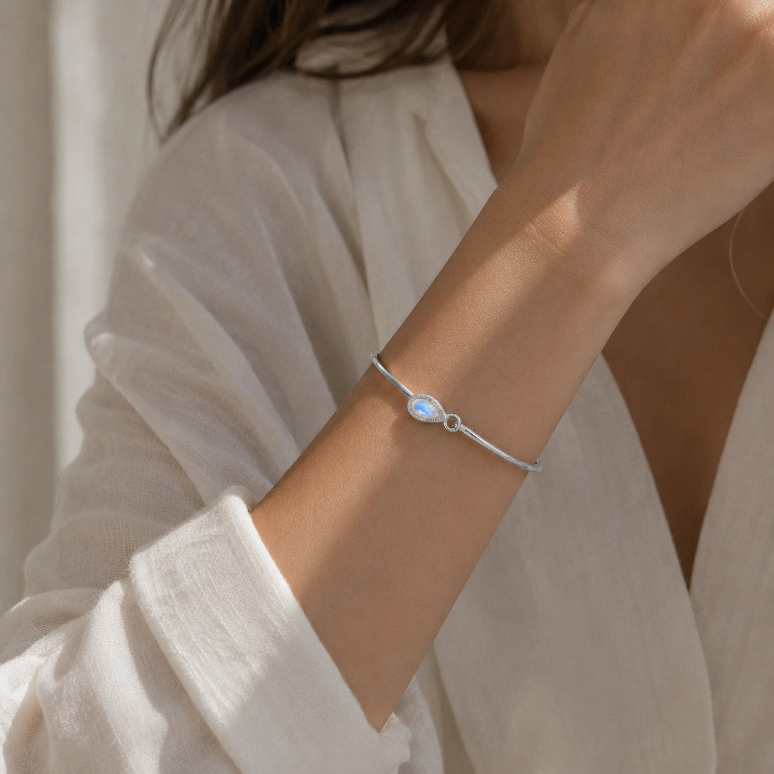 Moonstone_bracelet_in_gold_plated_silver_with_teardrop_moonstone_at_front_angle_view_on_soft_fabric_background