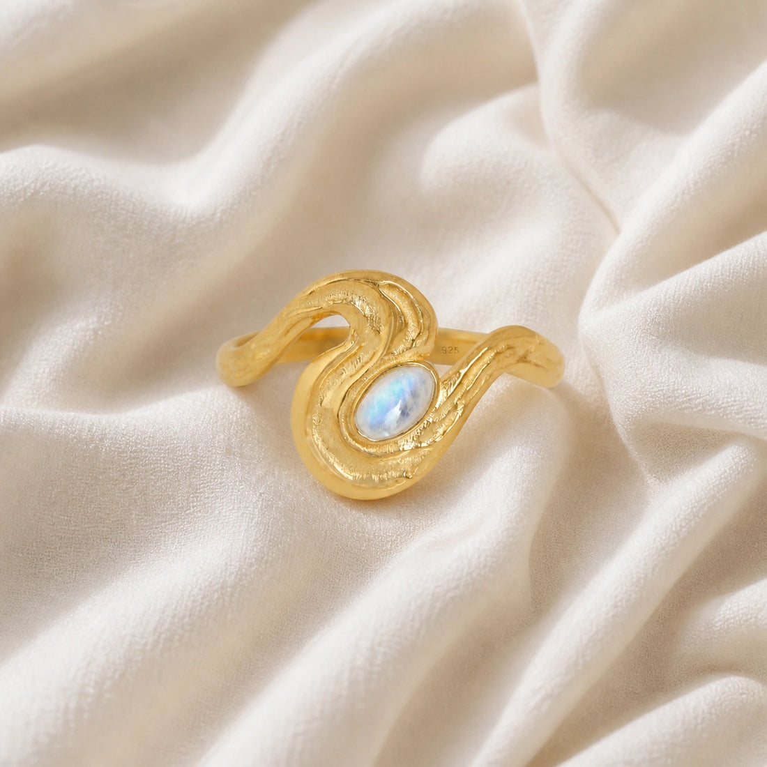 Moonstone_designer_ring_in_gold_plated_silver_with_moonstone_and_wave_band_shown_at_front_angle_view_on_soft_fabric_background