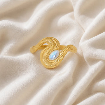 Moonstone_designer_ring_in_gold_plated_silver_with_moonstone_and_wave_band_shown_at_front_angle_view_on_soft_fabric_background