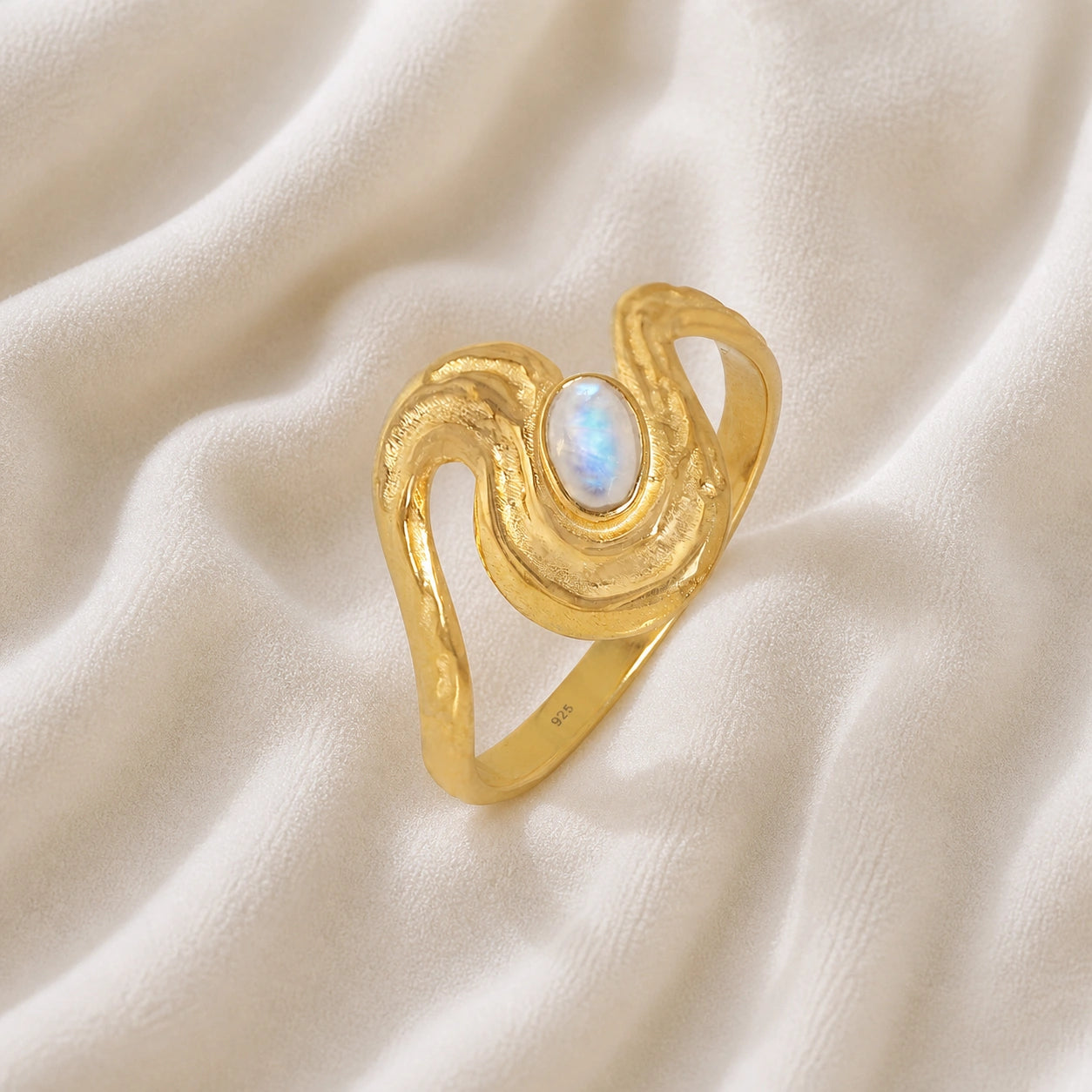 Moonstone_designer_ring_in_gold_plated_silver_with_moonstone_and_wave_band_shown_slightly_tilted_soft_fabric_background