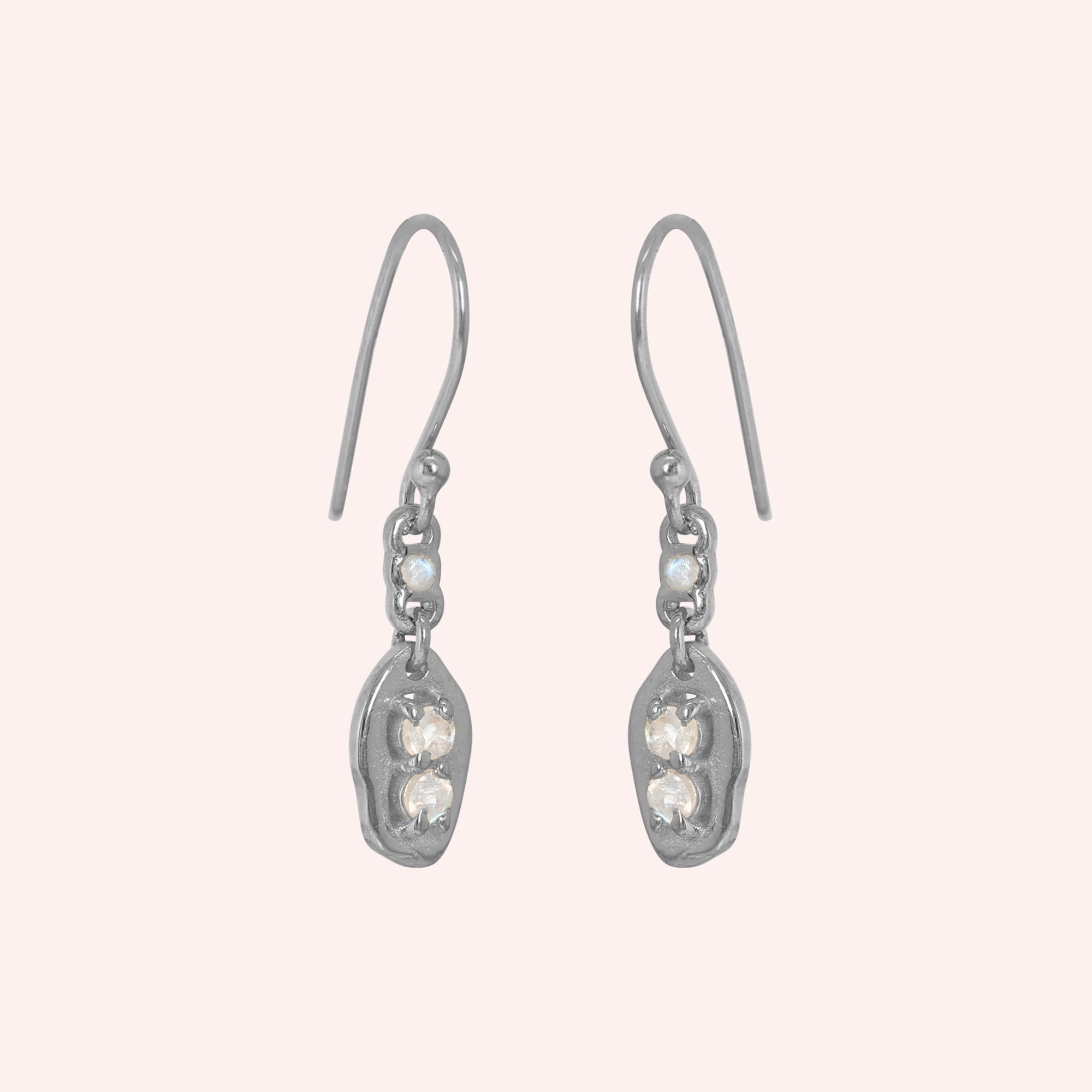 Moonstone_earrings_sterling_silver_drop_design_with_three_moonstones_in_slightly_angled_view_on_solid-pink_background
