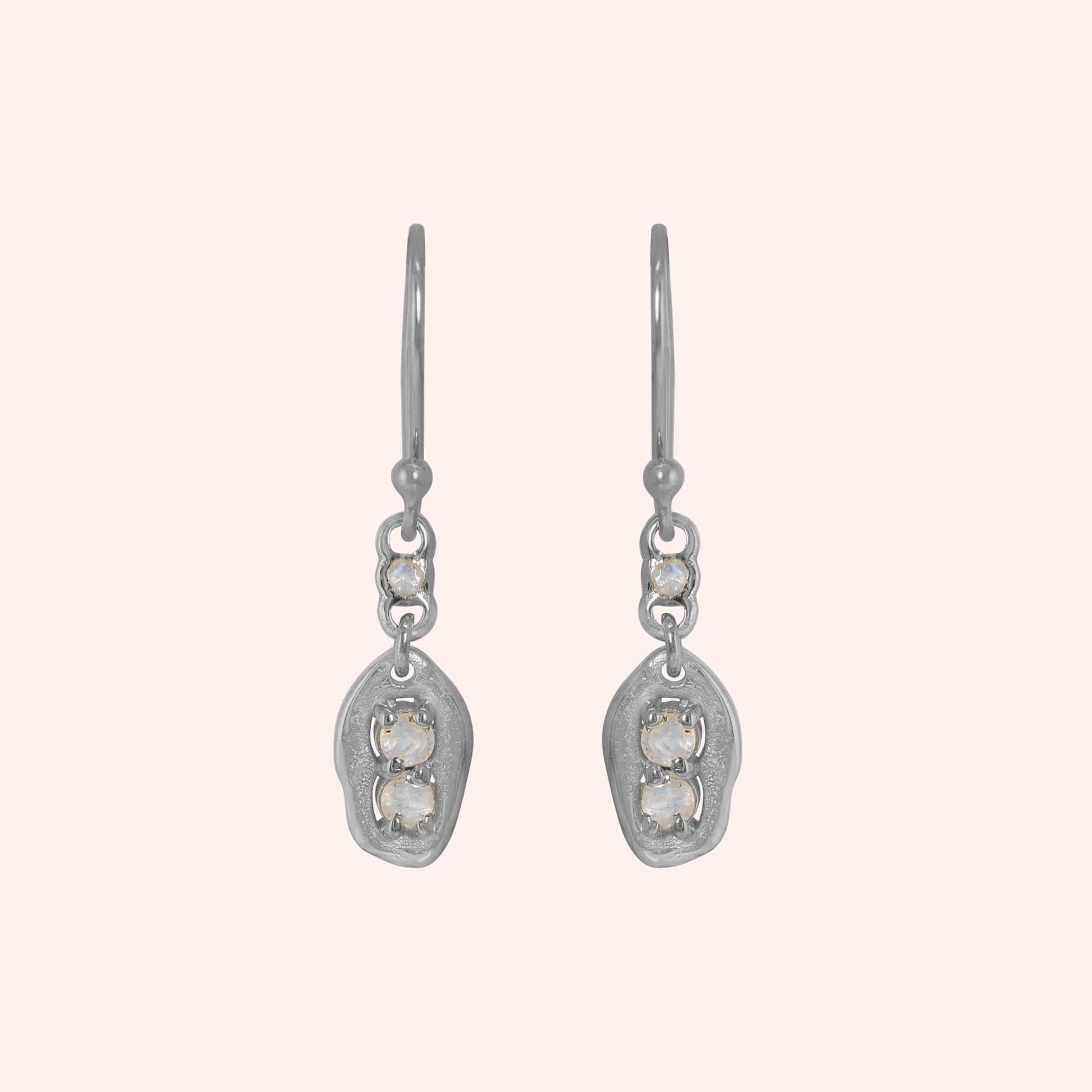 Moonstone_earrings_sterling_silver_drop_design_with_three_moonstones_in_front_angled_view_on_solid-pink_background