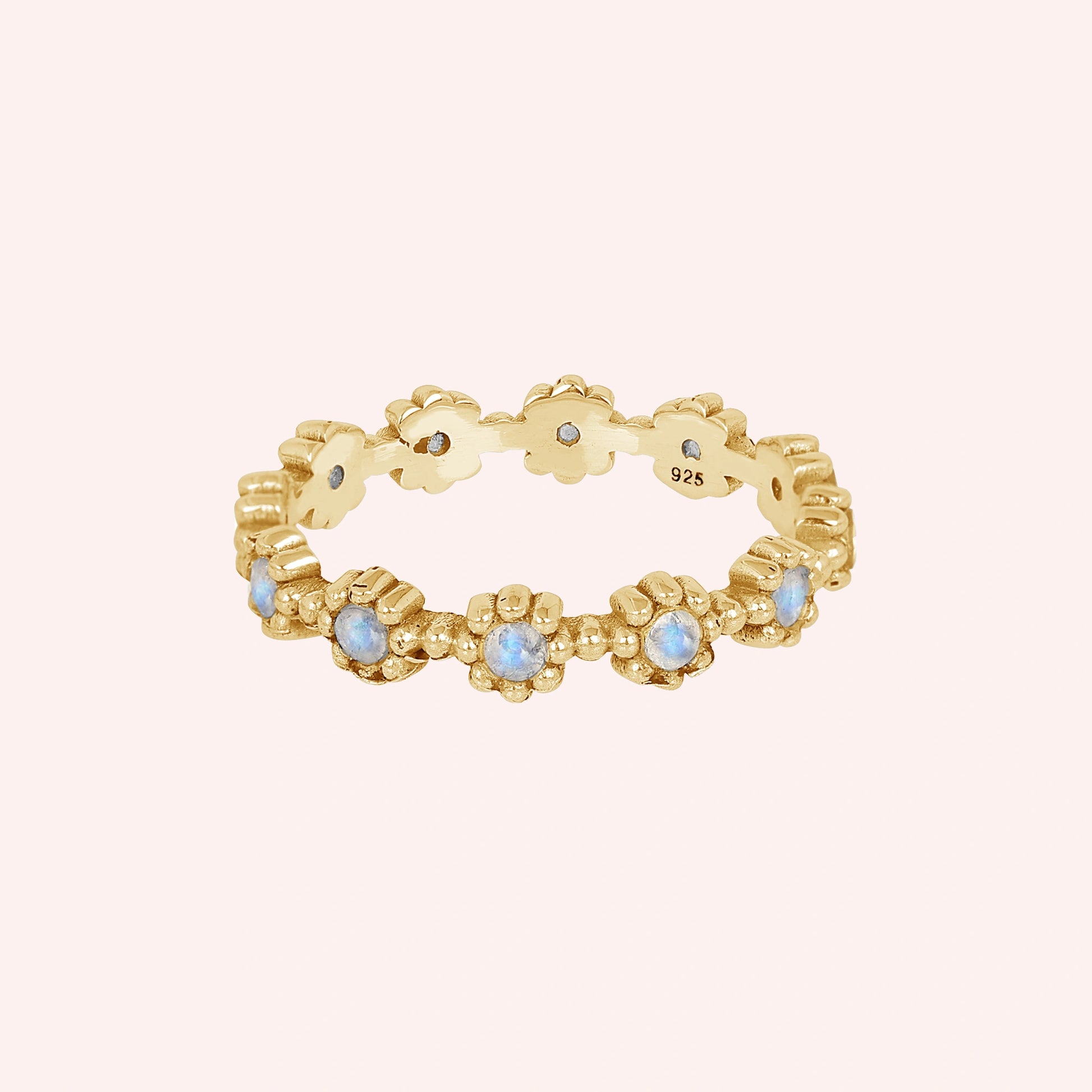 Gold-plated flower-designed moonstone ring full eternity band displaying round gems centered on a pink background straight angle.