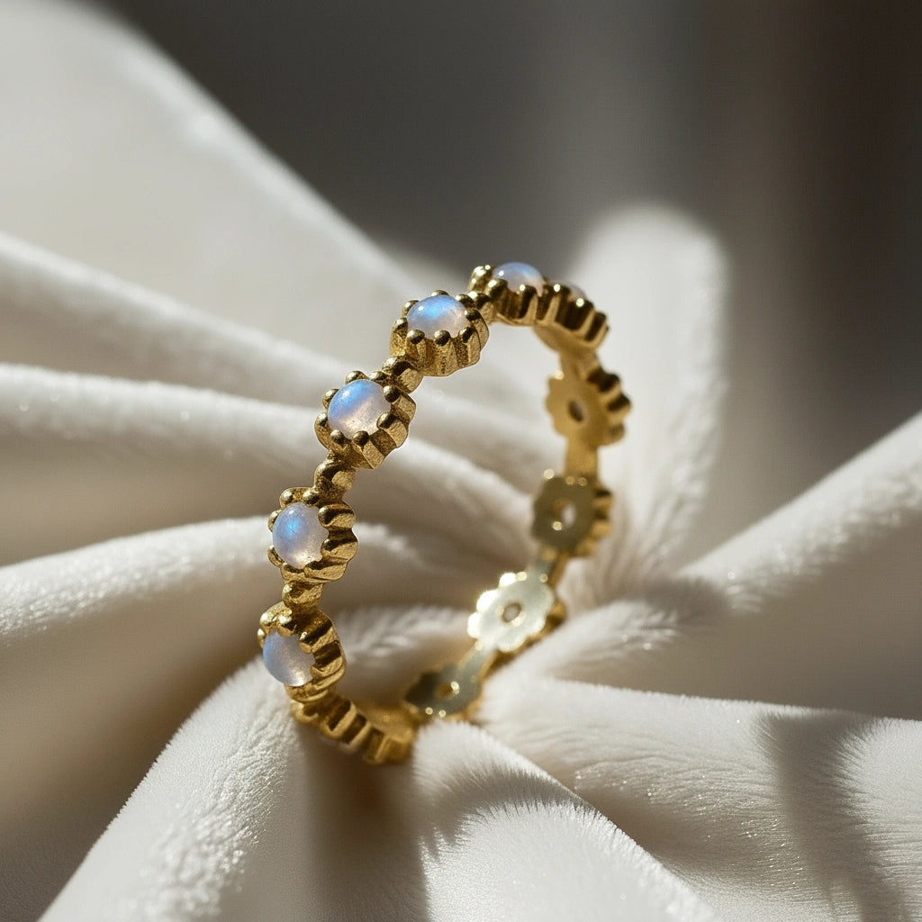 Gold-plated flower-designed moonstone ring full eternity band with round gems captured at an angle in the folds of velvet.