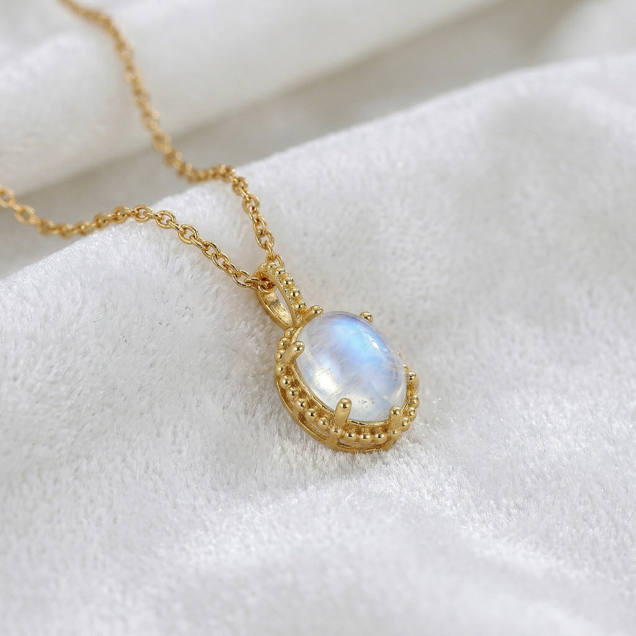 Moonstone_necklace_in_gold_plated_silver_and_glowing_moonstone_in_slightly_angled_view_on_soft_white_fabric_background
