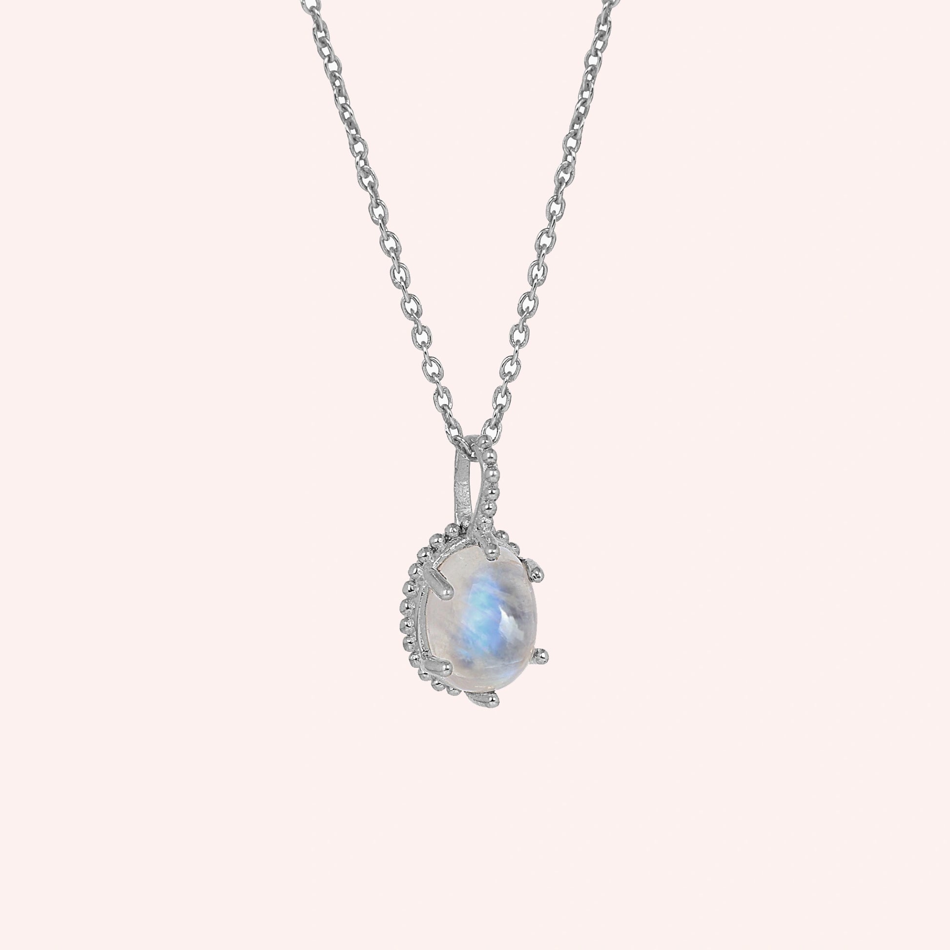 Moonstone_necklace_in_sterling_silver_and_glowing_moonstone_in_slightly_angled_view_on_solid_pink_background