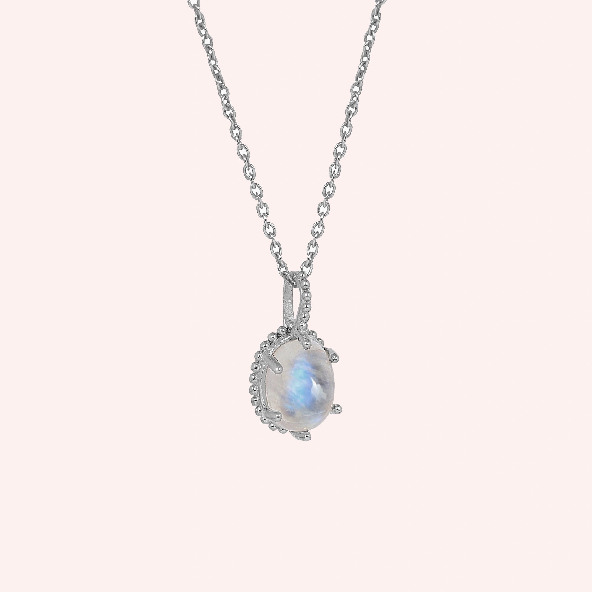 Moonstone_necklace_in_sterling_silver_and_glowing_moonstone_in_slightly_angled_view_on_solid_pink_background