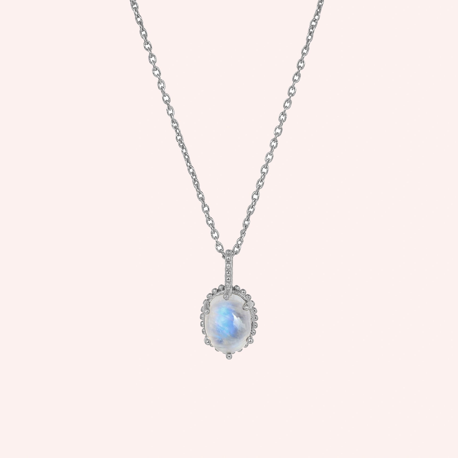Moonstone_necklace_in_sterling_silver_and_glowing_moonstone_in_front_angled_view_on_solid_pink_background