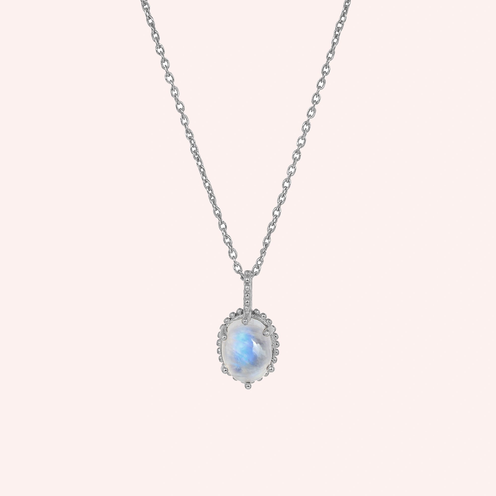 Moonstone_necklace_in_sterling_silver_and_glowing_moonstone_in_front_angled_view_on_solid_pink_background