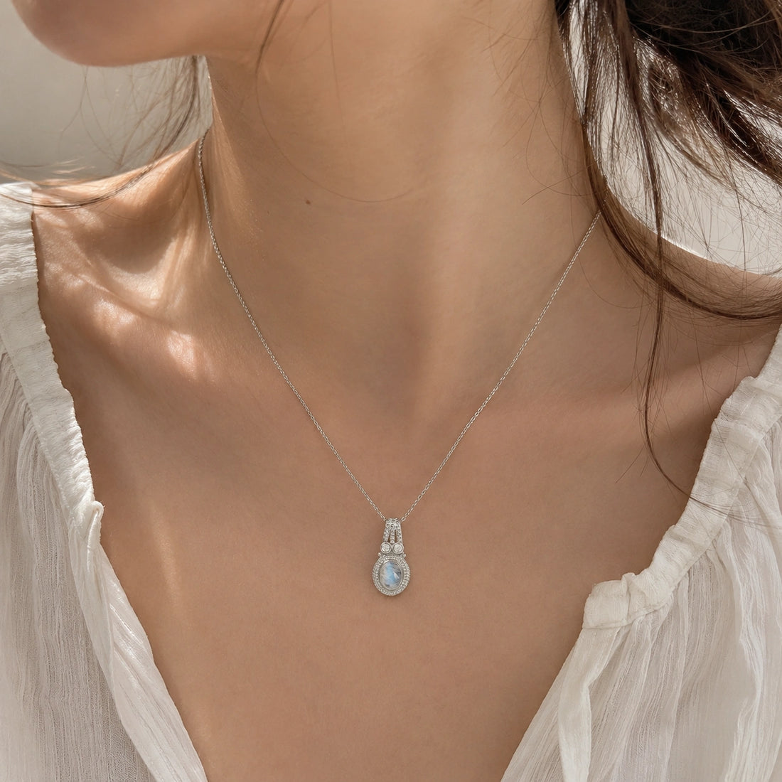 Moonstone_pendant_in_gold_plated_silver_with_oval_moonstone_and_CZ_stones_shown_in_slightly_angled_on_soft_fabric_background