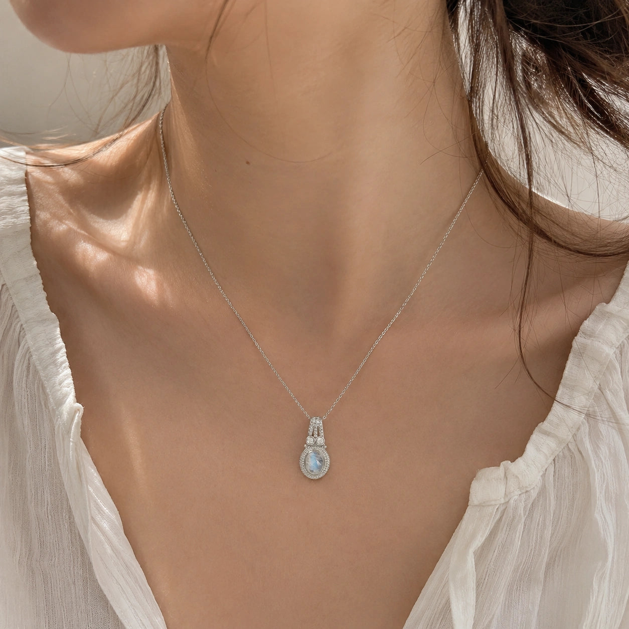Moonstone_pendant_in_sterling_silver_with_oval_moonstone_and_CZ_stones_worn_by_a_model