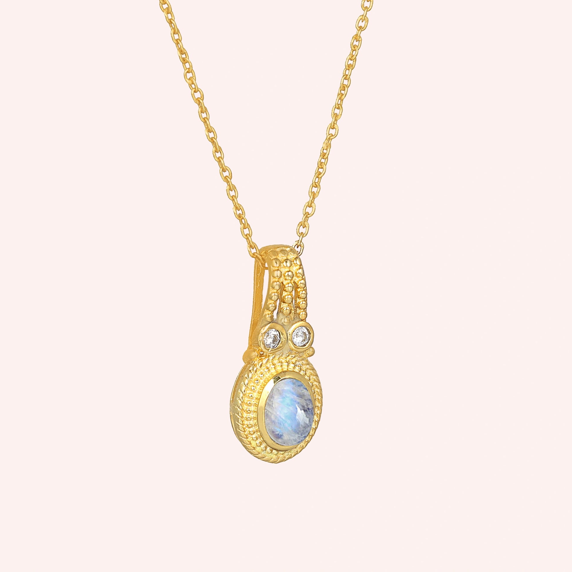 Moonstone_pendant_in_gold_plated_silver_with_oval_moonstone_and_CZ_stones_shown_in_slightly_angled_on_solid_pink_background
