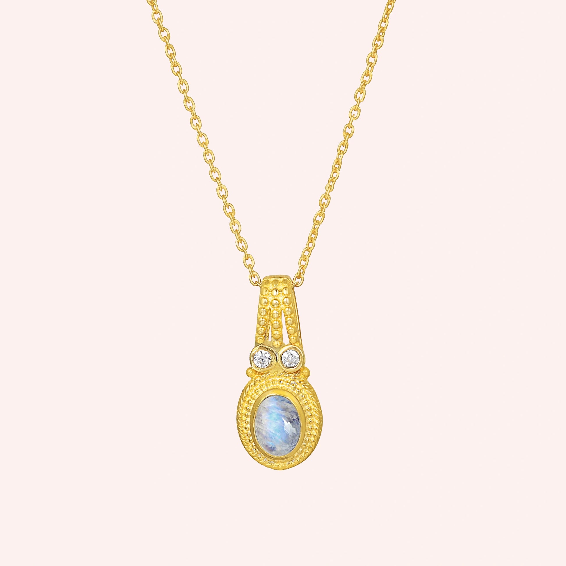 Moonstone_pendant_in_gold_plated_silver_with_oval_moonstone_and_CZ_stones_shown_in_front_angle_on_solid_pink_background