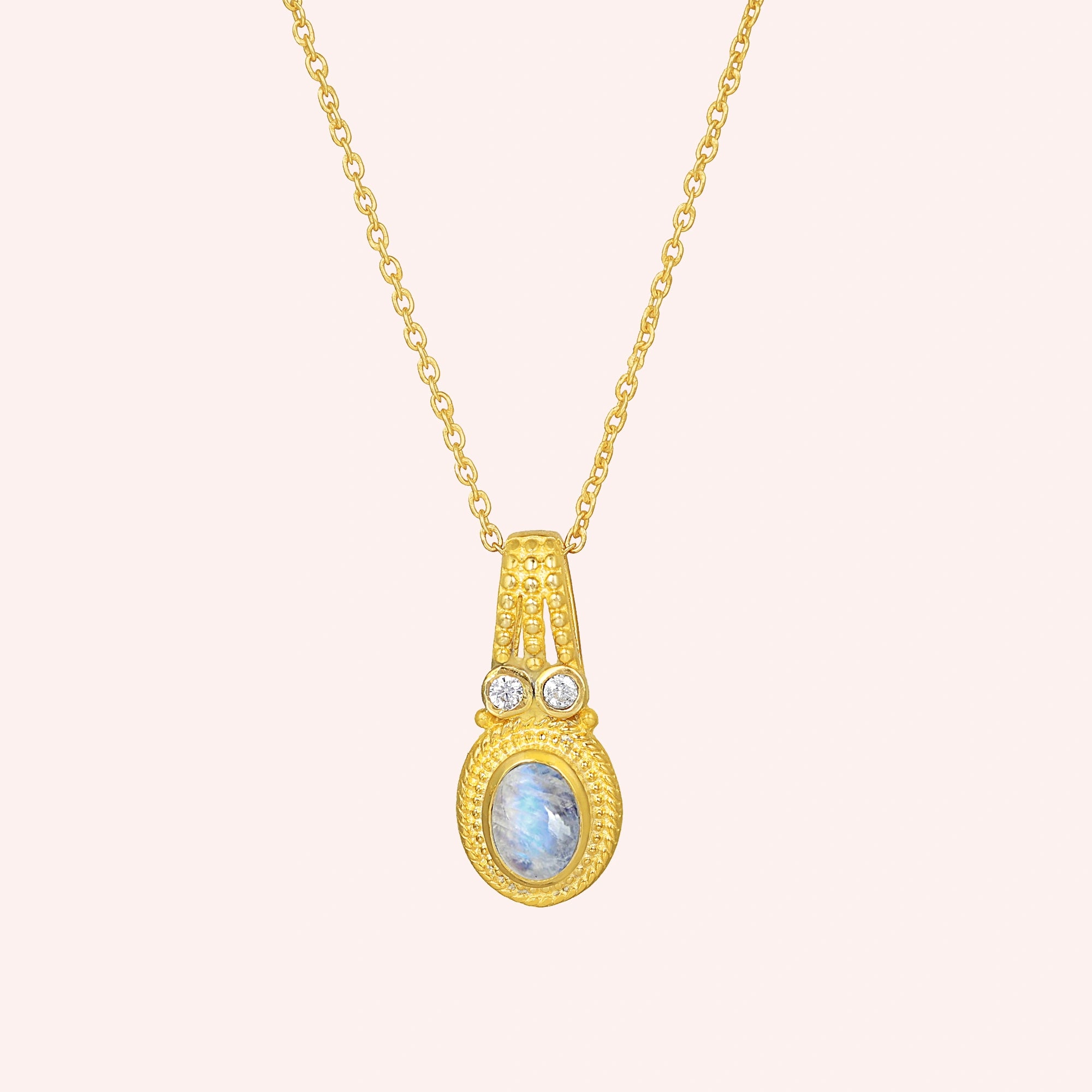 Moonstone_pendant_in_gold_plated_silver_with_oval_moonstone_and_CZ_stones_shown_in_front_angle_on_solid_pink_background