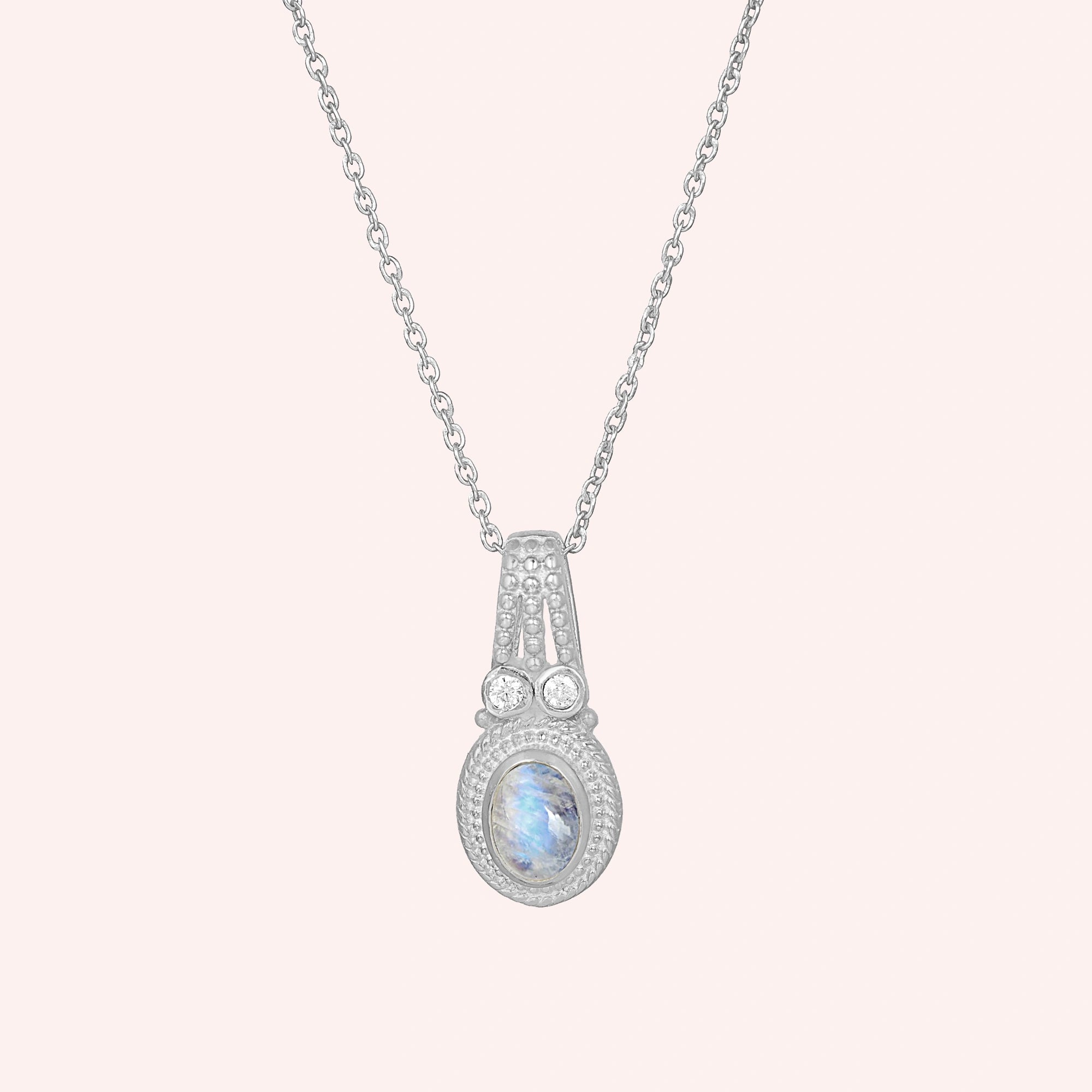 Moonstone_pendant_in_sterling_silver_with_oval_moonstone_and_CZ_stones_shown_in_front_angle_on_solid_pink_background