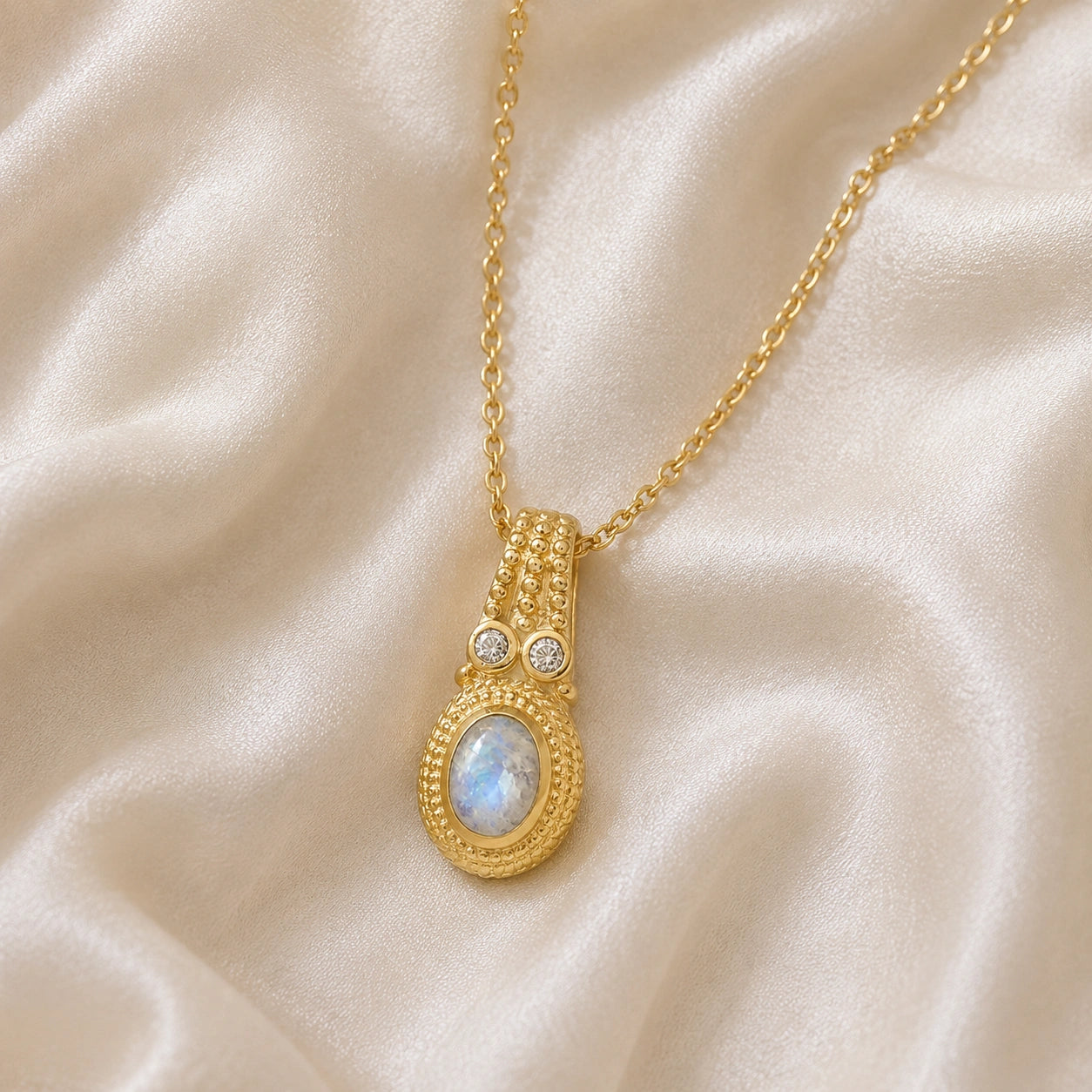 Moonstone_pendant_in_gold_plated_silver_with_oval_moonstone_and_CZ_stones_shown_in_front_angle_on_soft_fabric_background
