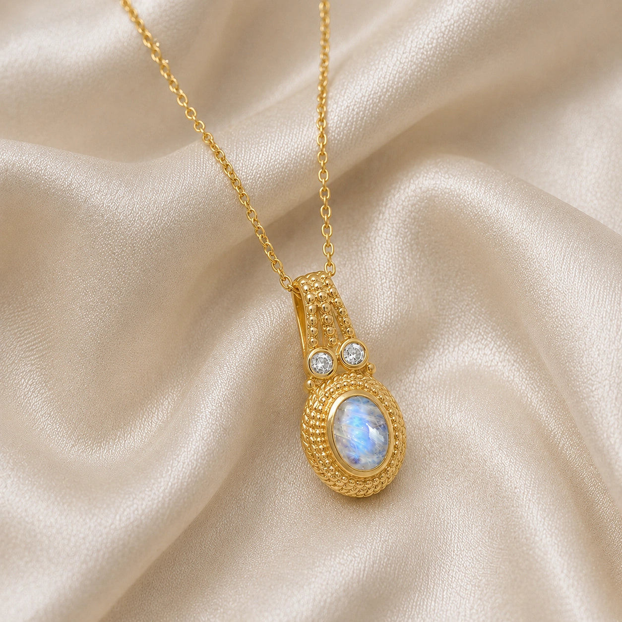 Moonstone_pendant_in_gold_plated_silver_with_oval_moonstone_and_CZ_stones_shown_in_slightly_angled_on_soft_fabric_background