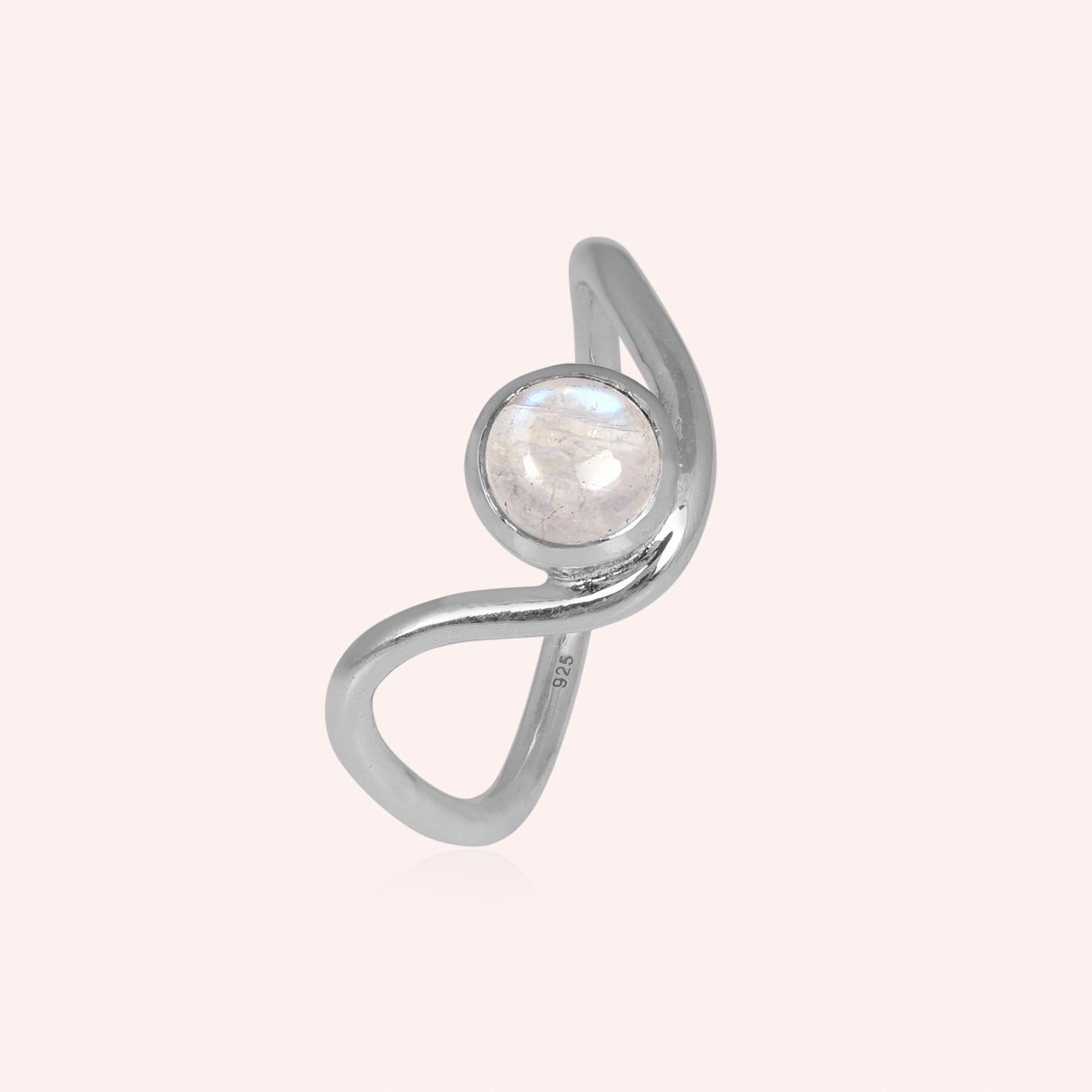 A silver moonstone ring featuring a round moonstone and a wave ring band design at a side angle over a pink plain background