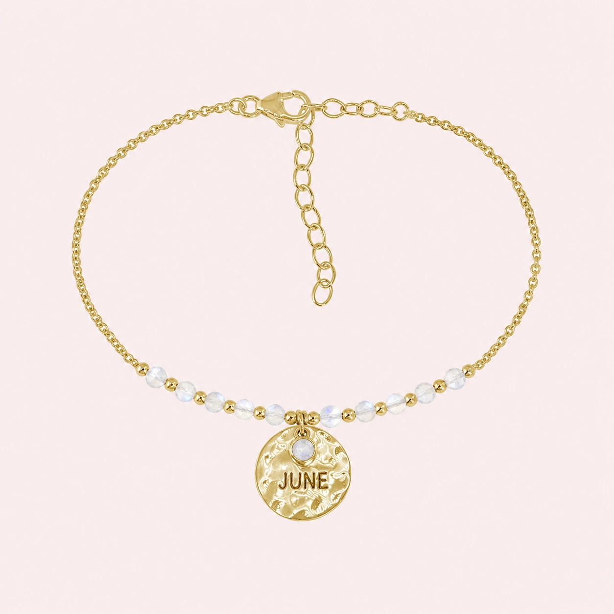 Birthstone_bracelet_in_gold_plated_silver_with_June_charm_and_moonstone_beads_on_fine_chain_on_solid_pink_background