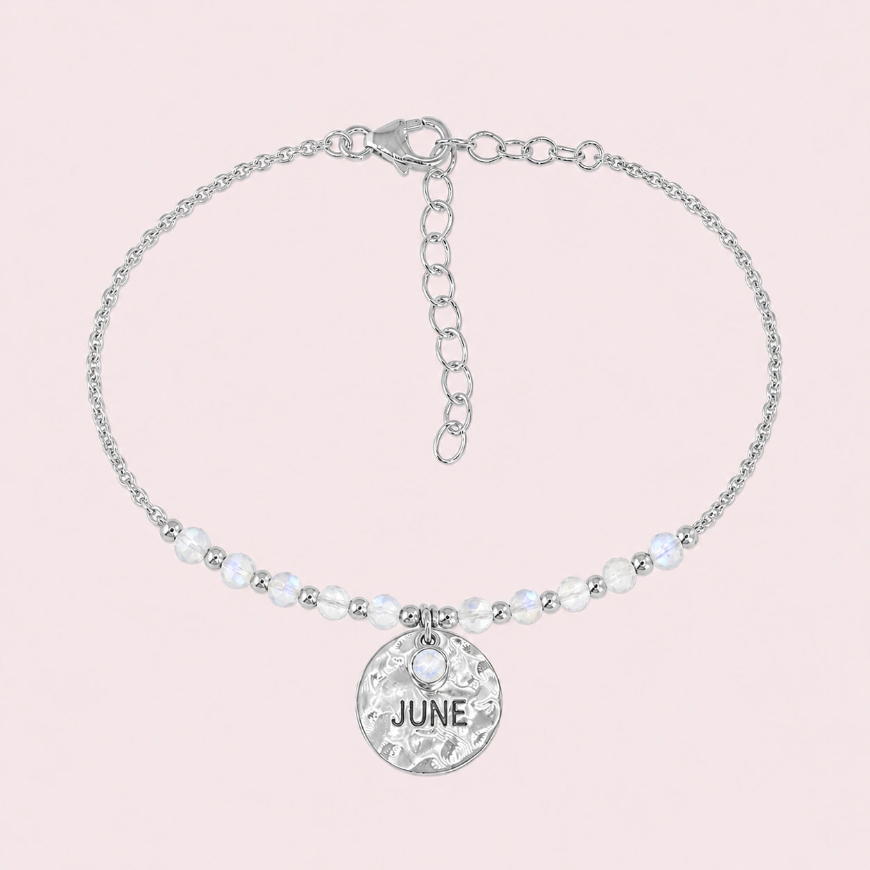 Birthstone_bracelet_in_sterling_silver_with_June_charm_and_moonstone_beads_on_fine_chain_on_solid_pink_background