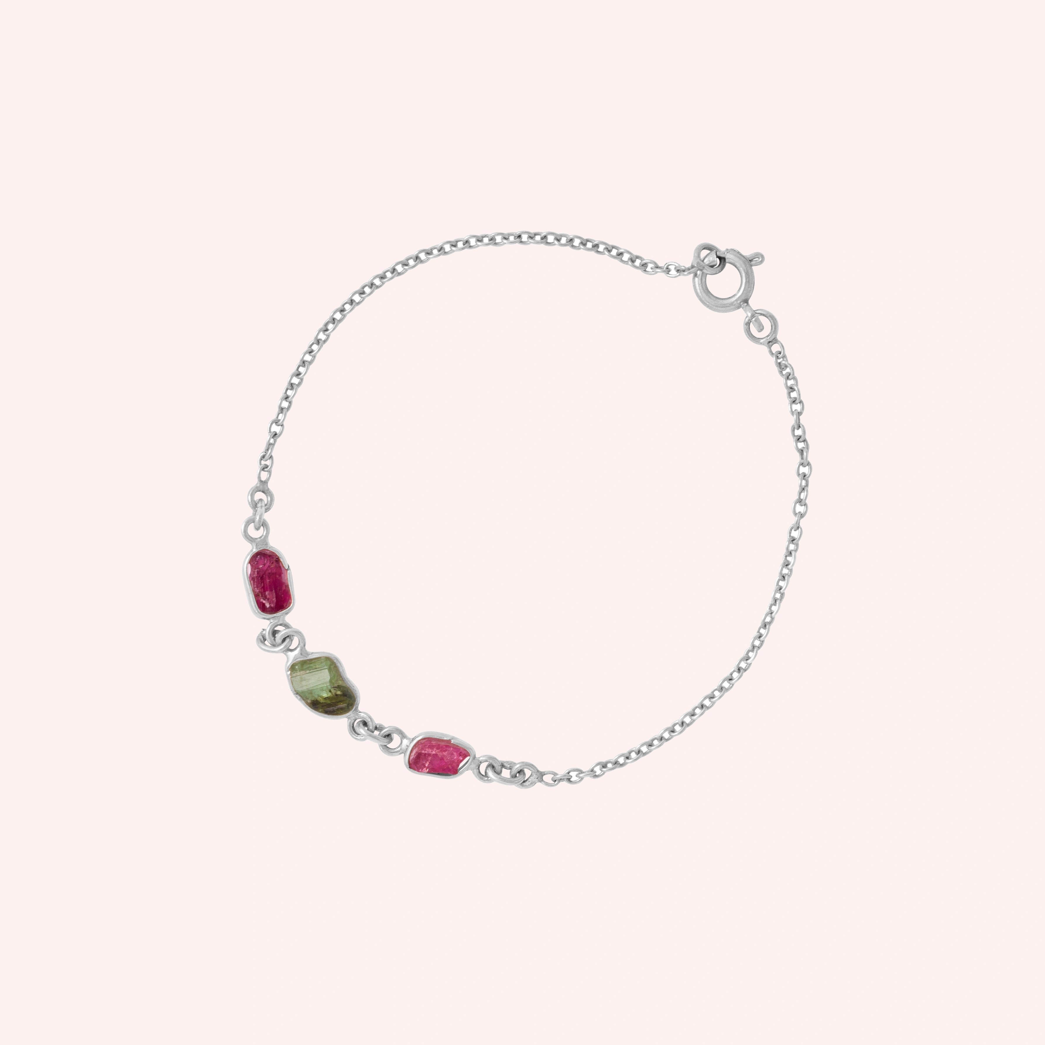 Multi_tourmaline_bracelet_in_sterling_silver_with_pink_and_green_tourmaline_at_slight_angle_view_on_solid_pink_backgrou