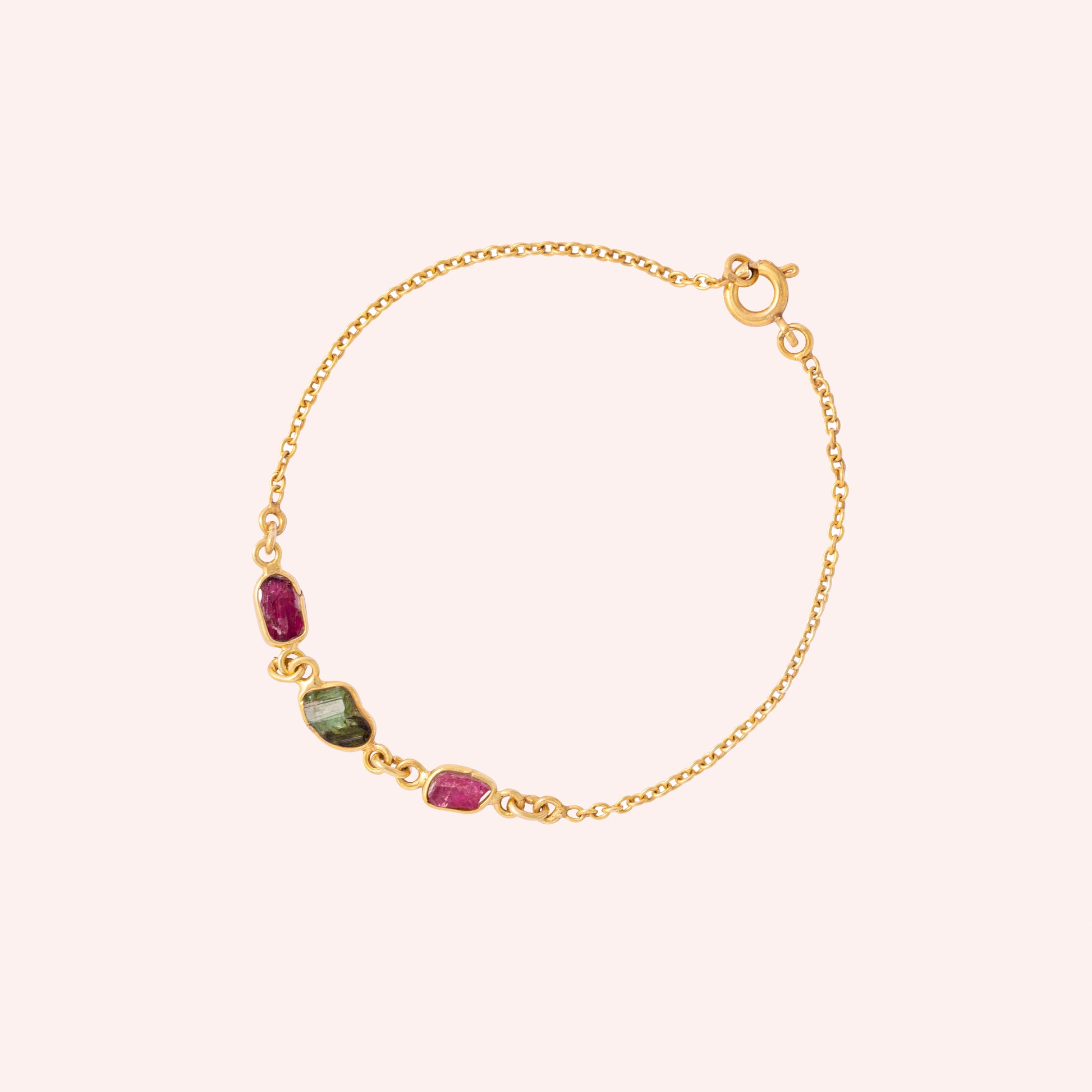 Multi_tourmaline_bracelet_in_gold_plated_silver_with_pink_and_green_tourmaline_at_slight_angle_view_on_solid_pink_backgrou