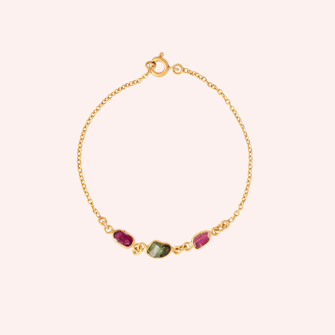 Multi_tourmaline_bracelet_in_gold_plated_silver_with_pink_and_green_tourmaline_at_front_angle_view_on_solid_pink_backgrou