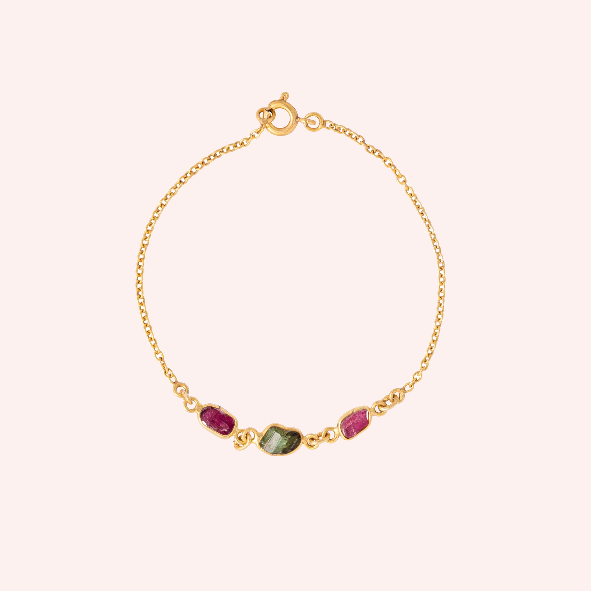 Multi_tourmaline_bracelet_in_gold_plated_silver_with_pink_and_green_tourmaline_at_front_angle_view_on_solid_pink_backgrou