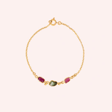 Multi_tourmaline_bracelet_in_gold_plated_silver_with_pink_and_green_tourmaline_at_front_angle_view_on_solid_pink_backgrou