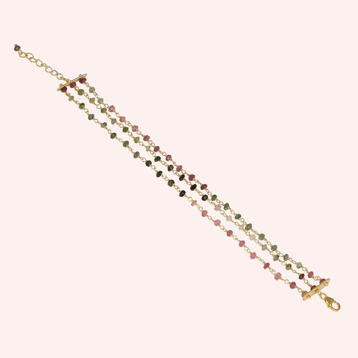 Tourmaline_bracelet_in_gold_plated_silver_bracelet_with_multi_tourmaline_stones_on_a_solid_pink_background