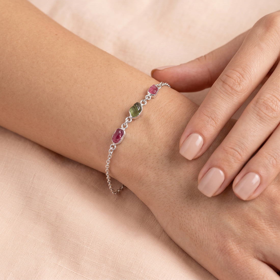 Multi_tourmaline_bracelet_in_gold_plated_silver_with_pink_and_green_tourmaline_at_front_angle_view_on_soft_fabric_backgrou