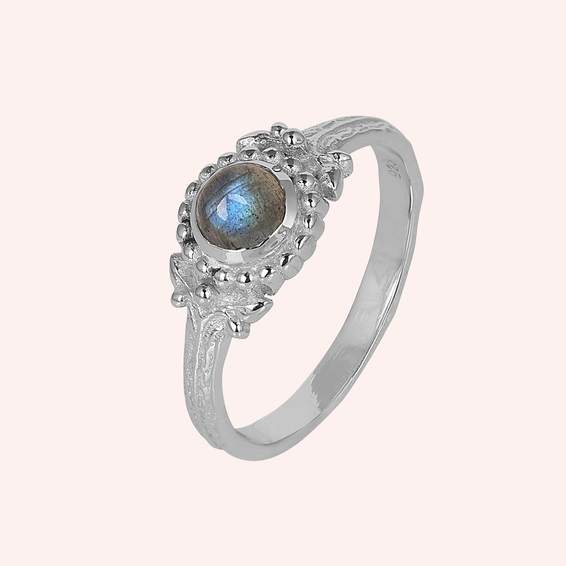 Natural_stone_ring_sterling_silver_with_round_labradorite_and_detailed_band_slightly_tilted_view_on_solid_pink_background