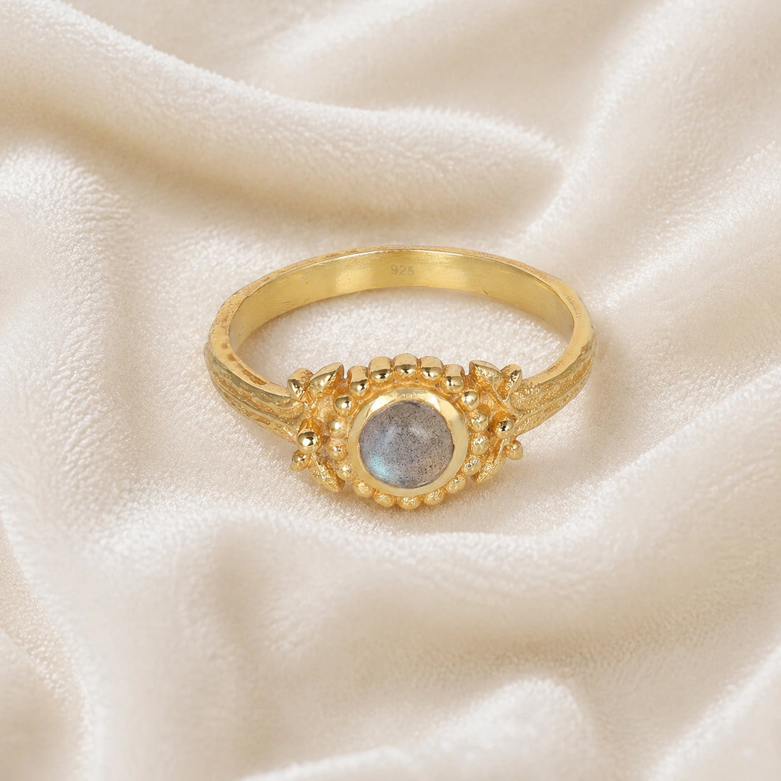 Natural_stone_ring_gold_plated_silver_with_round_labradorite_and_detailed_band_front_angle_view_on_soft_fabric_background