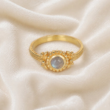 Natural_stone_ring_gold_plated_silver_with_round_labradorite_and_detailed_band_front_angle_view_on_soft_fabric_background