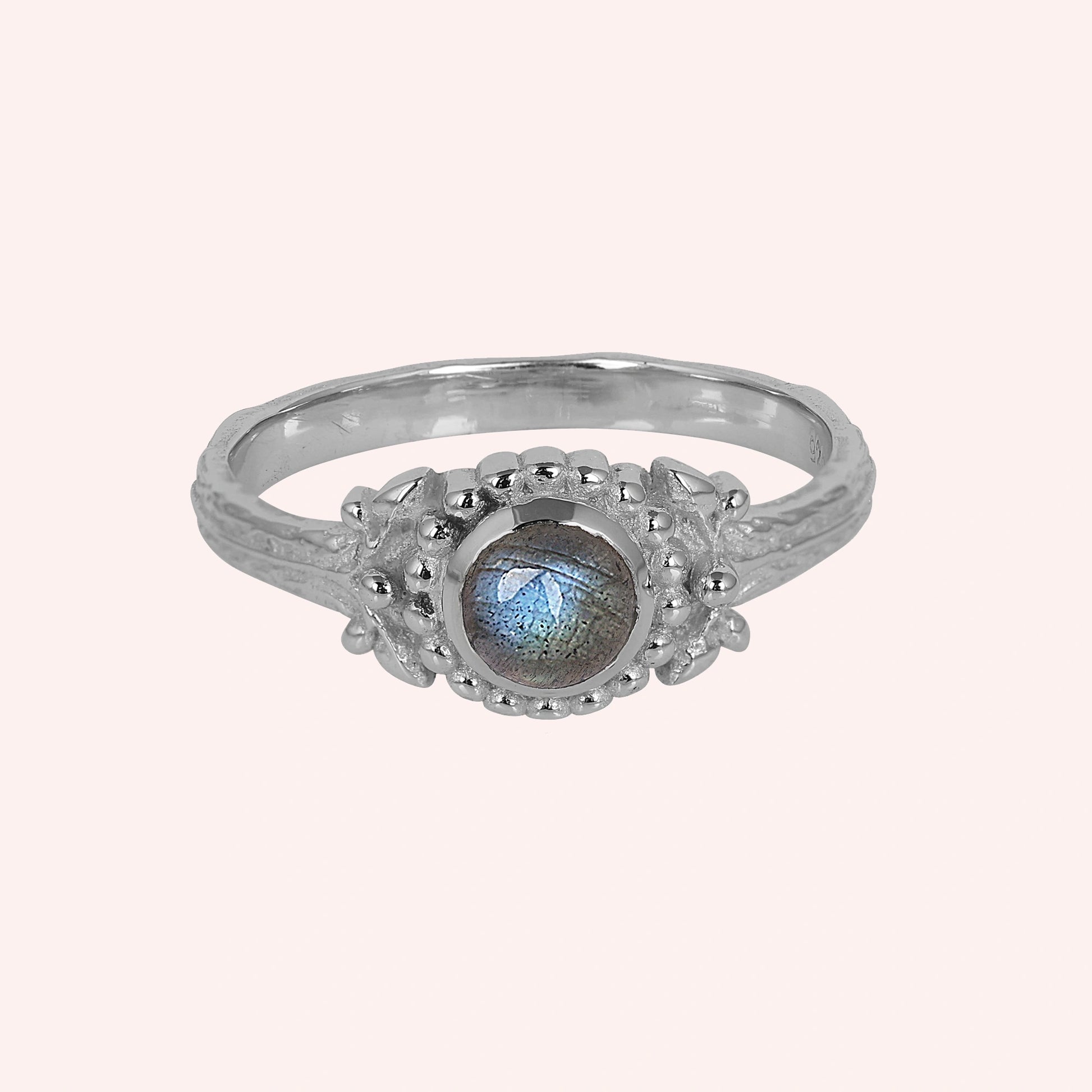 Natural_stone_ring_sterling_silver_with_round_labradorite_and_detailed_band_front_angle_view_on_solid_pink_background