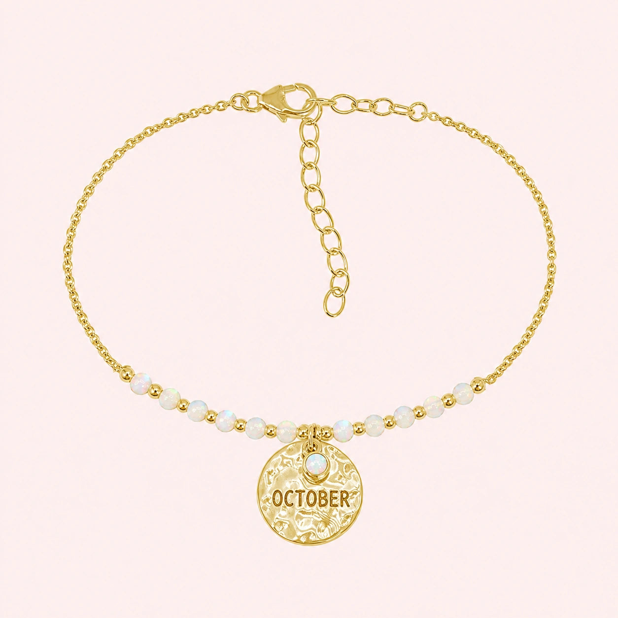 Birthstone_bracelet_in_gold_plated_silver_with_October_charm_and_opal_beads_on_fine_chain_on_solid_pink_background