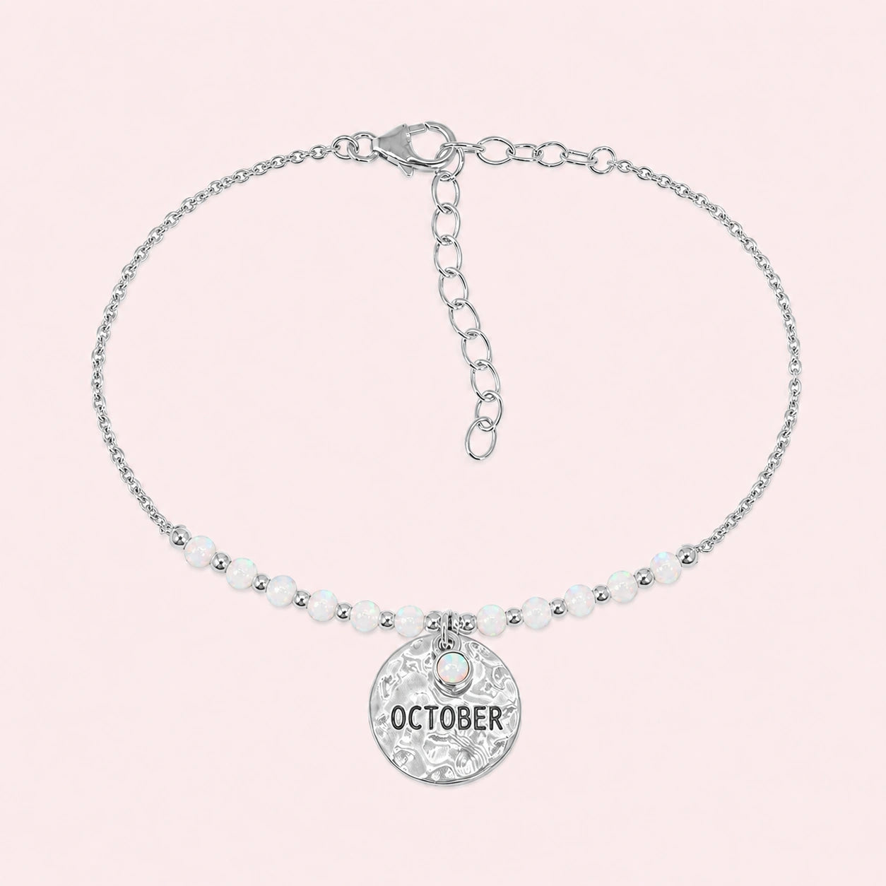 Birthstone_bracelet_in_stering_silver_with_October_charm_and_opal_beads_on_fine_chain_on_solid_pink_background