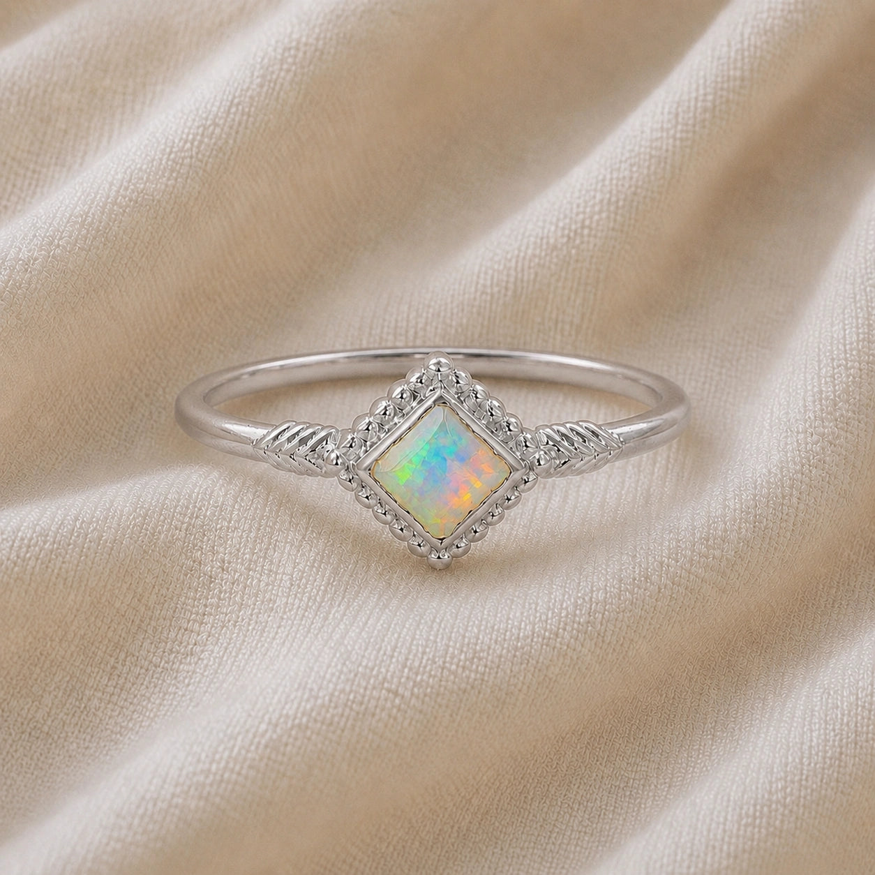 Princess_cut_ring_sterling_silver_with_square_opal_and_detailed_band_front_angle_view_on_soft_fabric_background