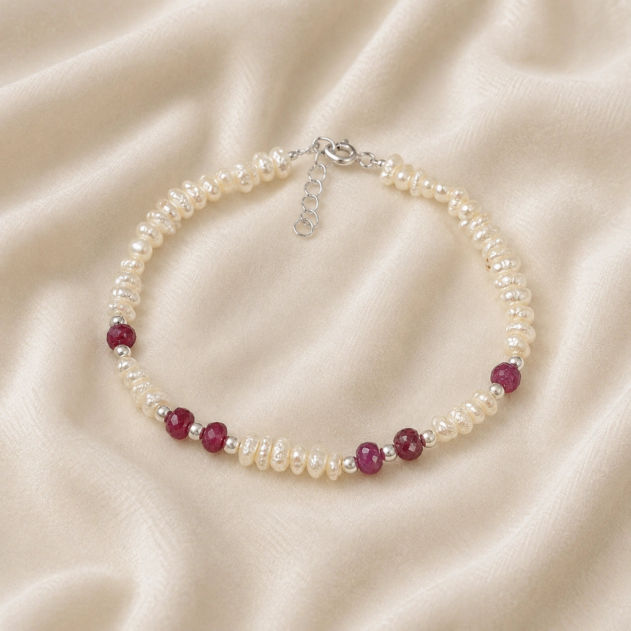 Pearl_bracelet_with_pearl_and_ruby_stones_in_sterling_silver_at_front_angle_view_on_soft_fabric_background